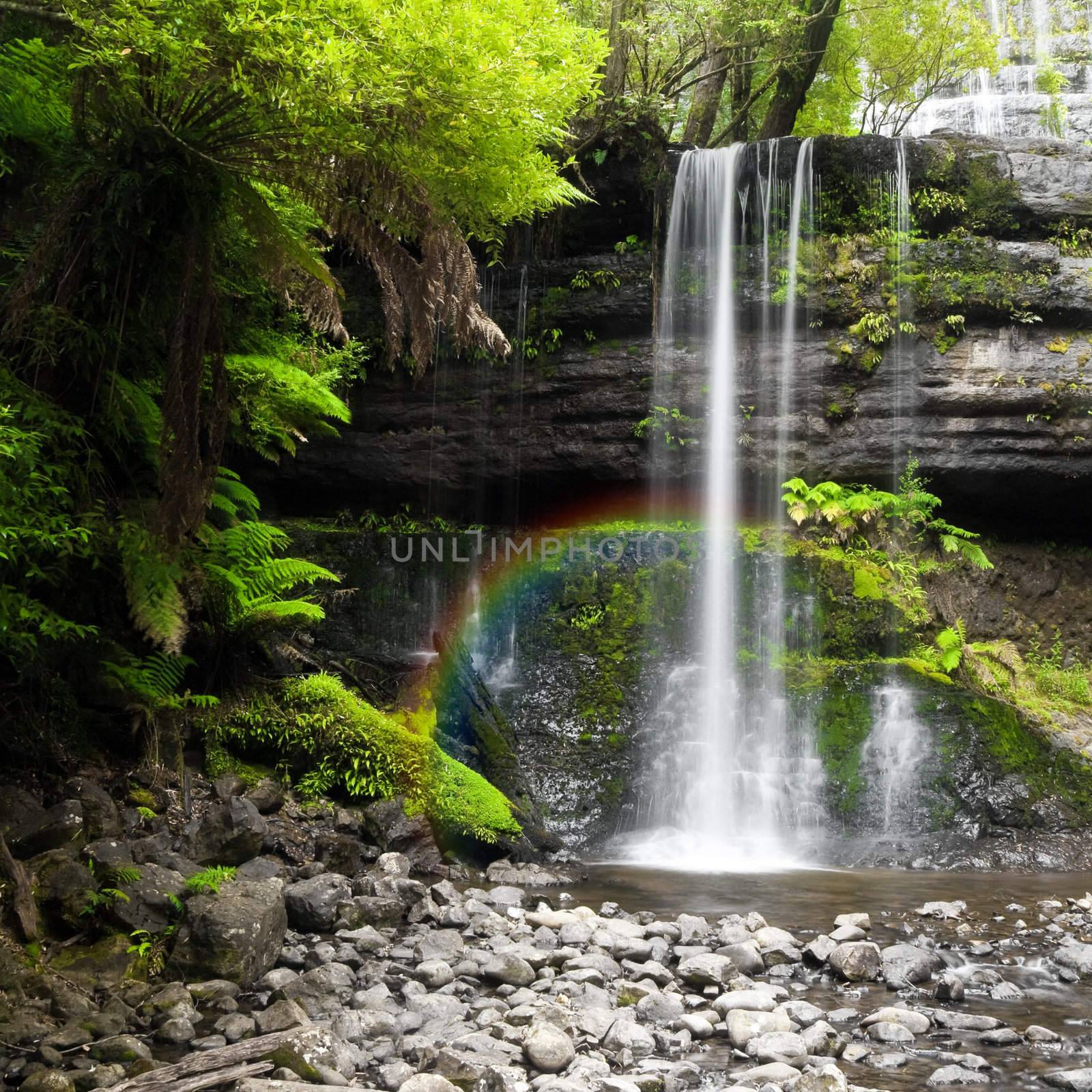 A photography of a nice rainforest waterfall in Australia with a little rainbow