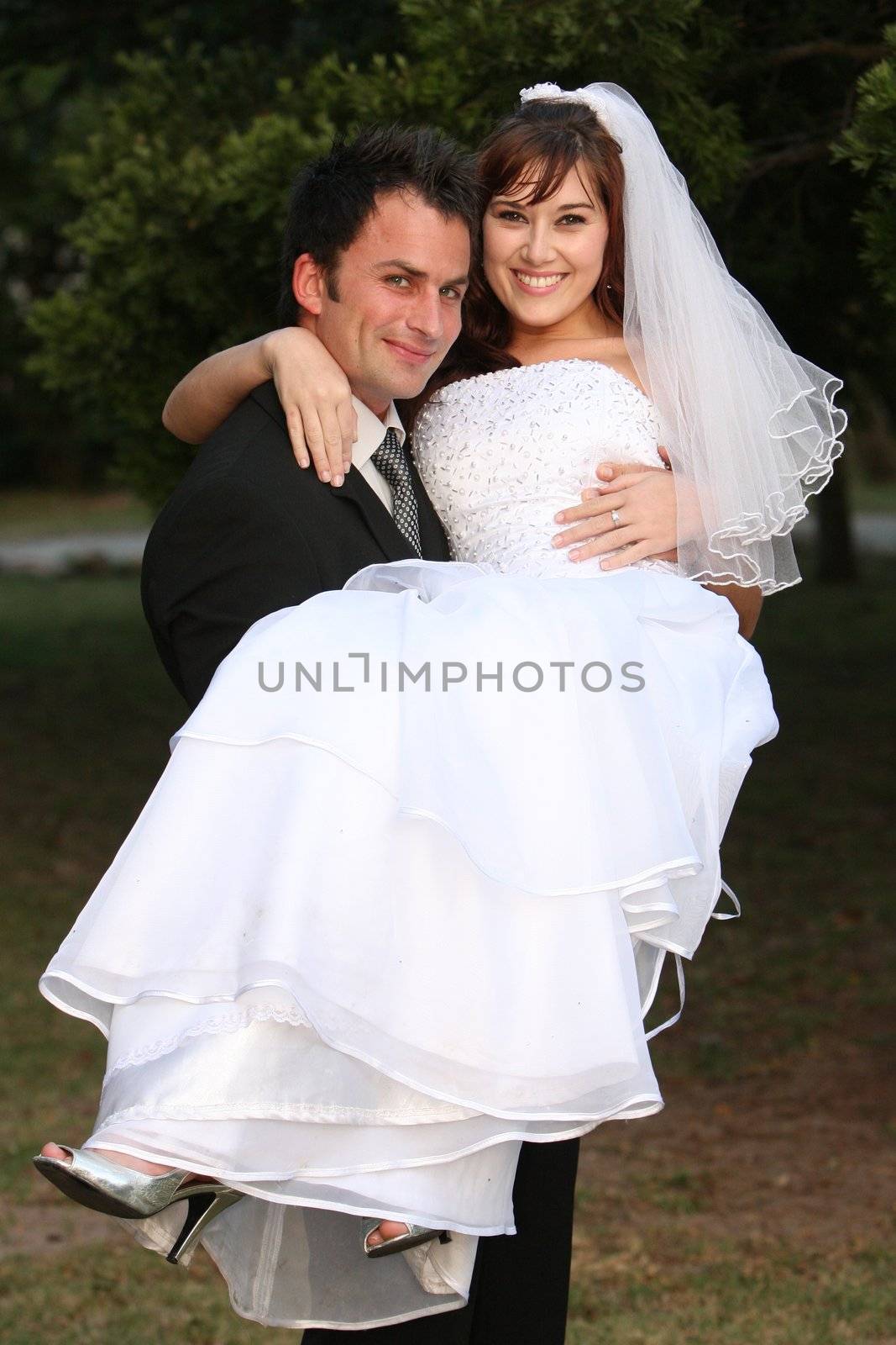 Beautiful wedding couple with the bride been carried by the groom