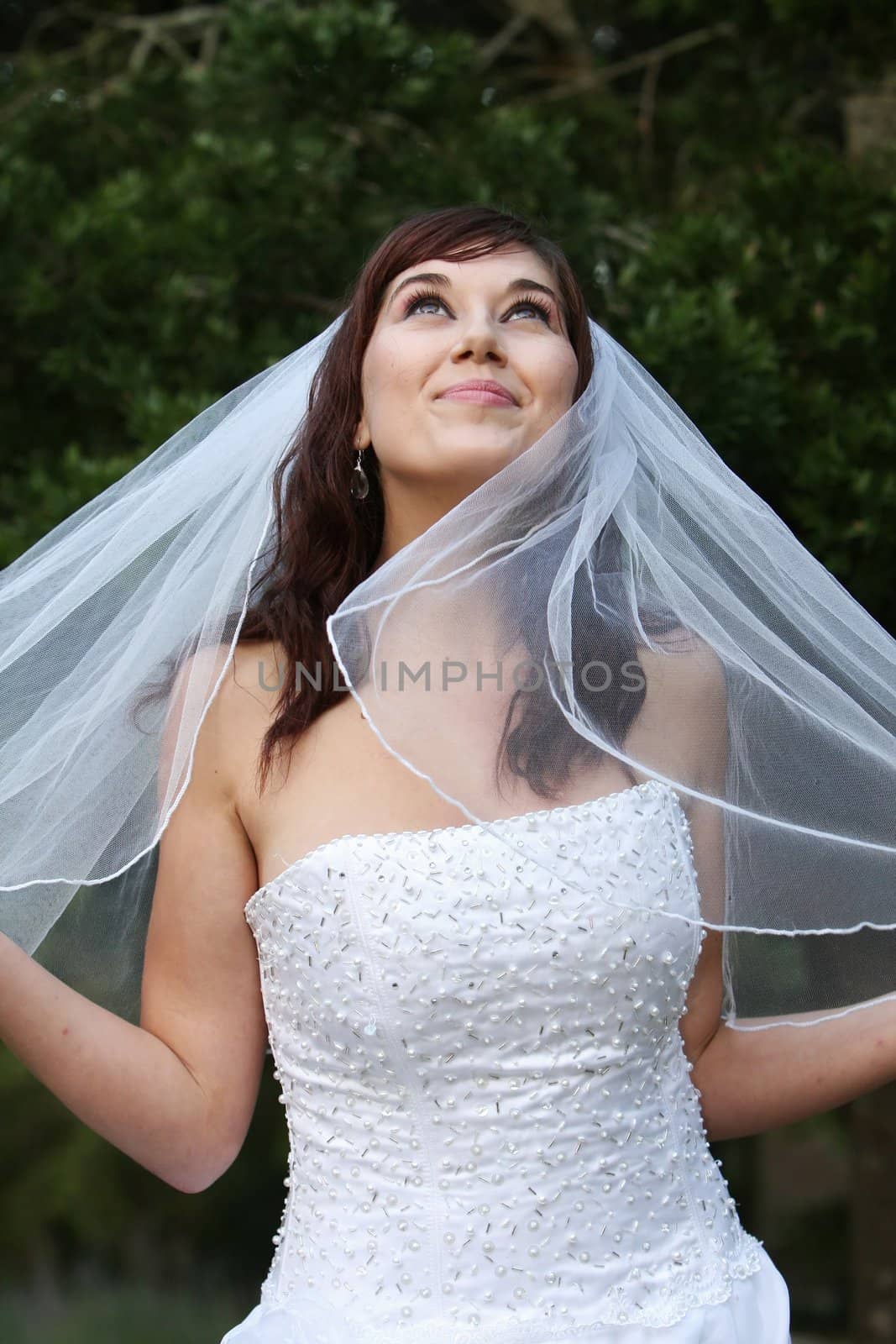 Stunning bride with lovely smile looking up in a beautiful wedding dress