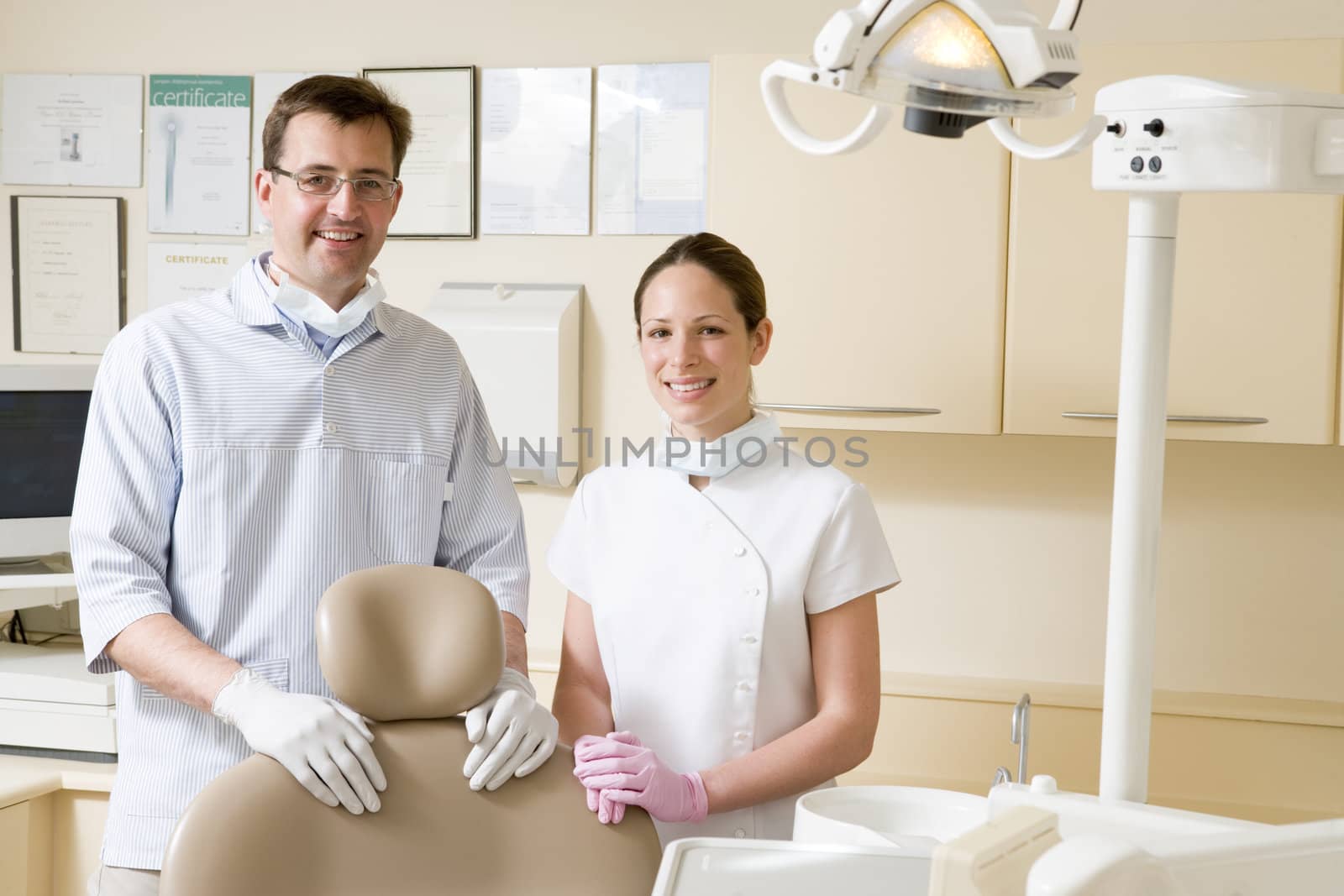 Dentist and assistant in exam room smiling by MonkeyBusiness