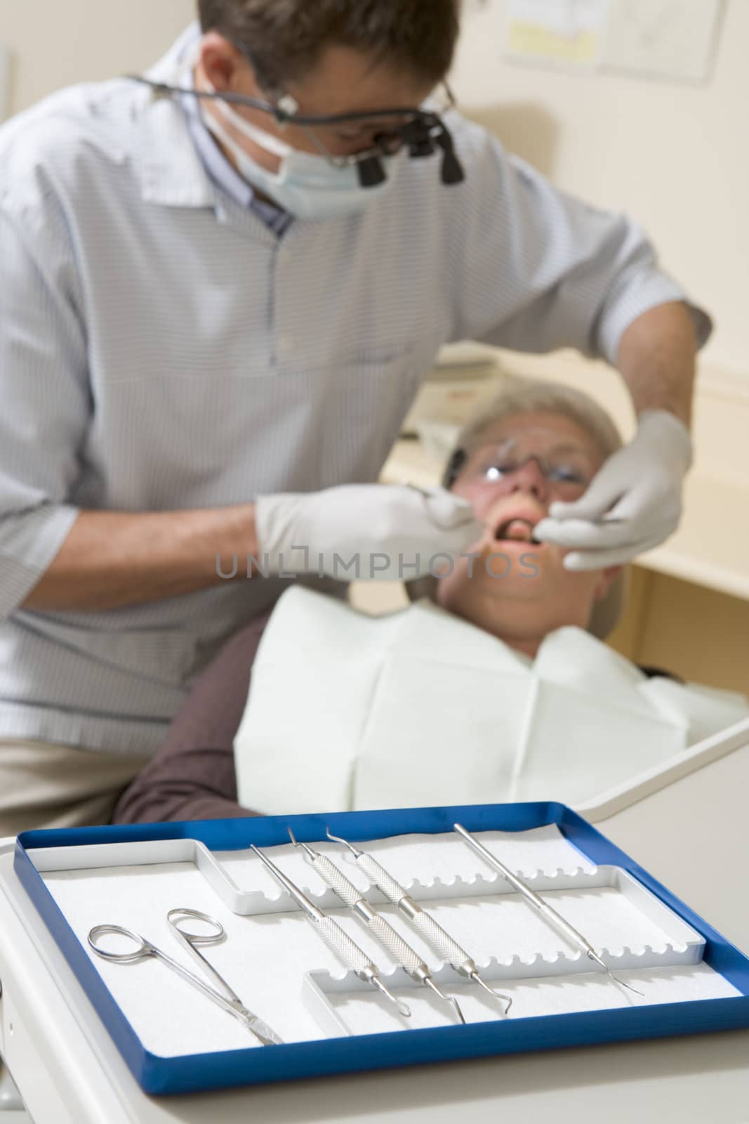 Dentist in exam room with woman in chair by MonkeyBusiness