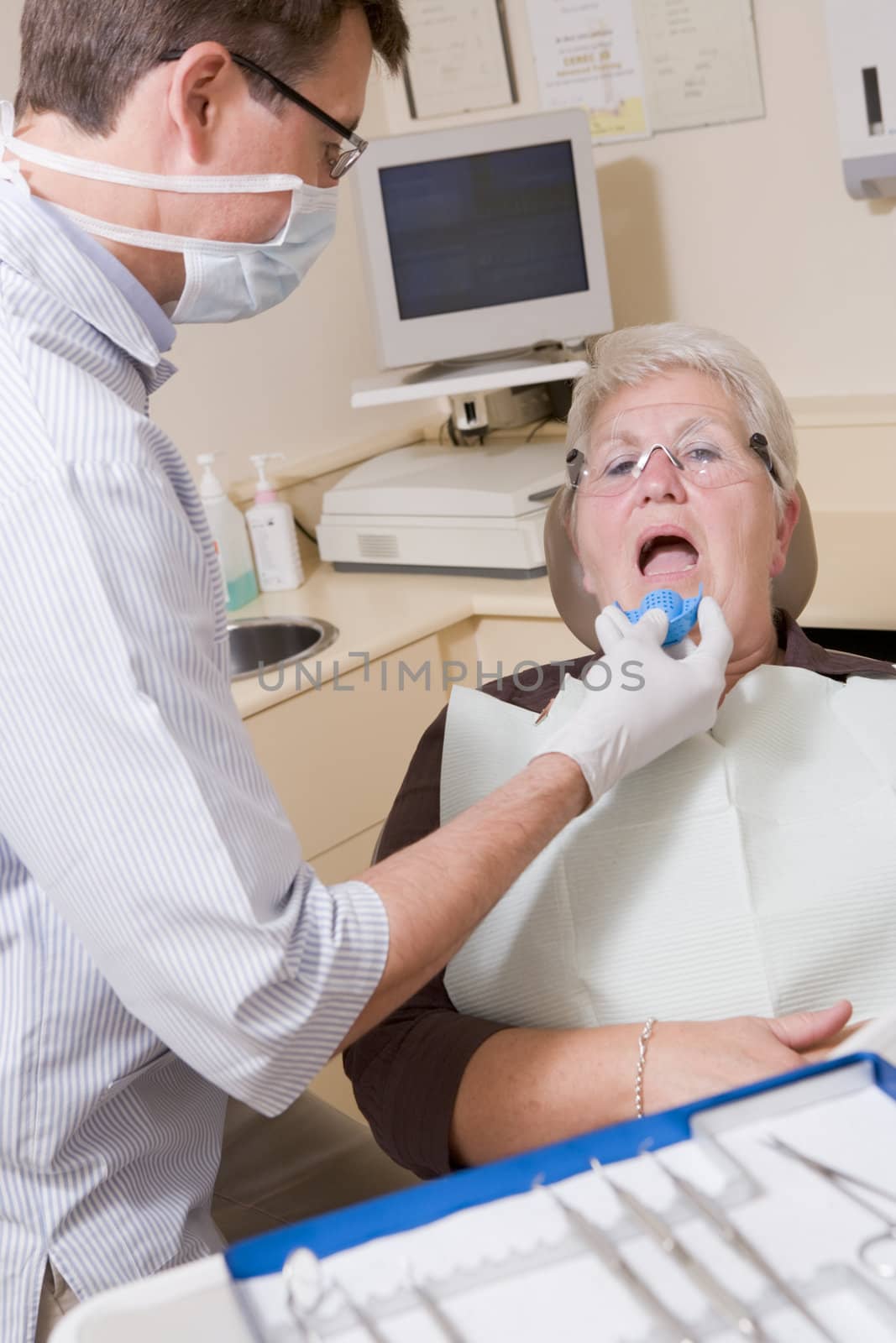 Dentist in exam room with woman in chair by MonkeyBusiness