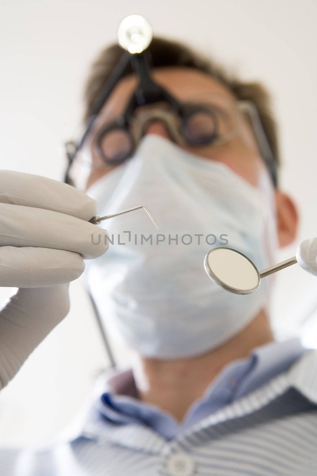 Dentist holding pick and mirror by MonkeyBusiness