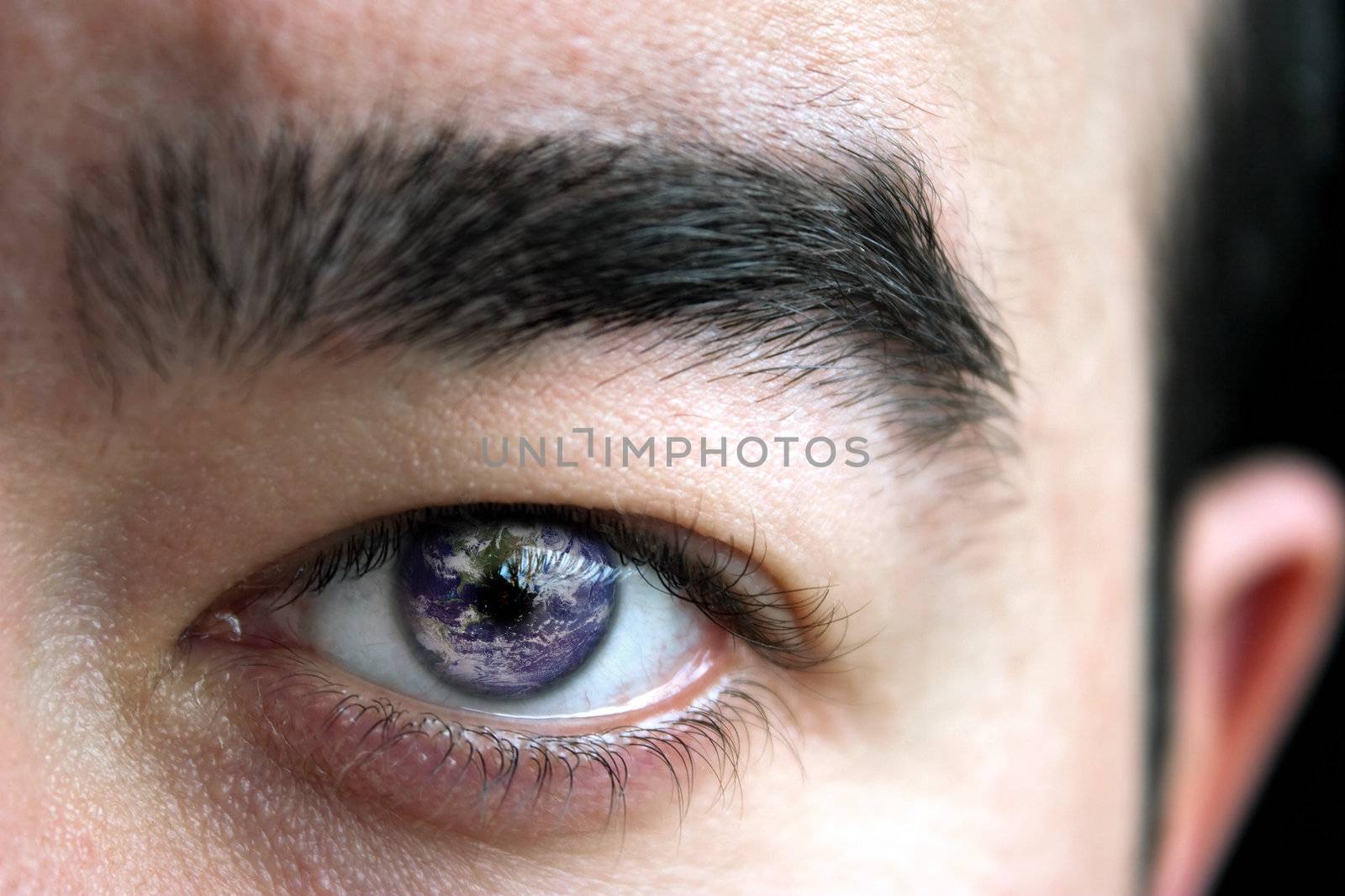 Closeup of a mans eye and eyebrow with the earth superimposed in his iris.
