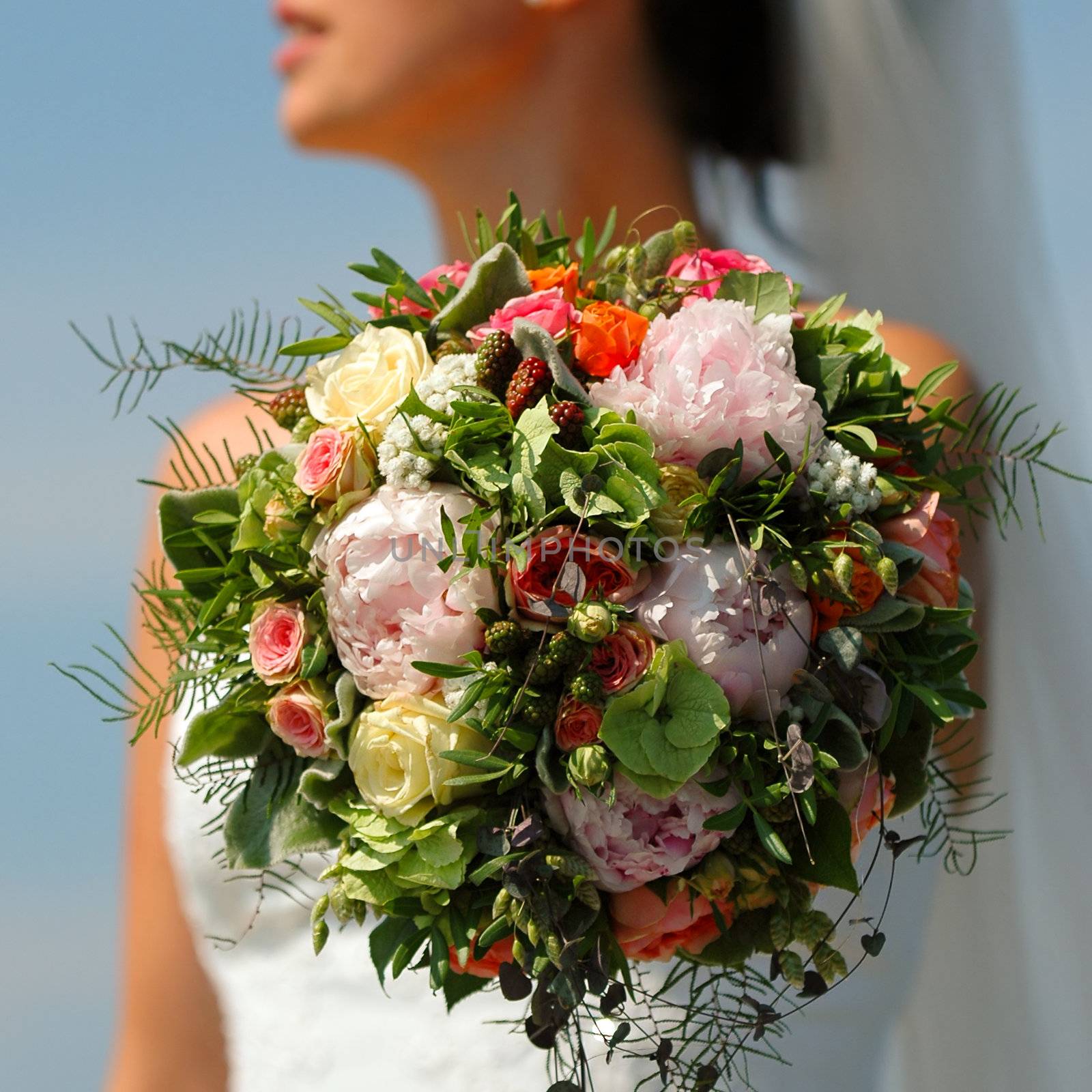 Bride holding flower boquet. The flower boquet is in focus and the bride is in blur.