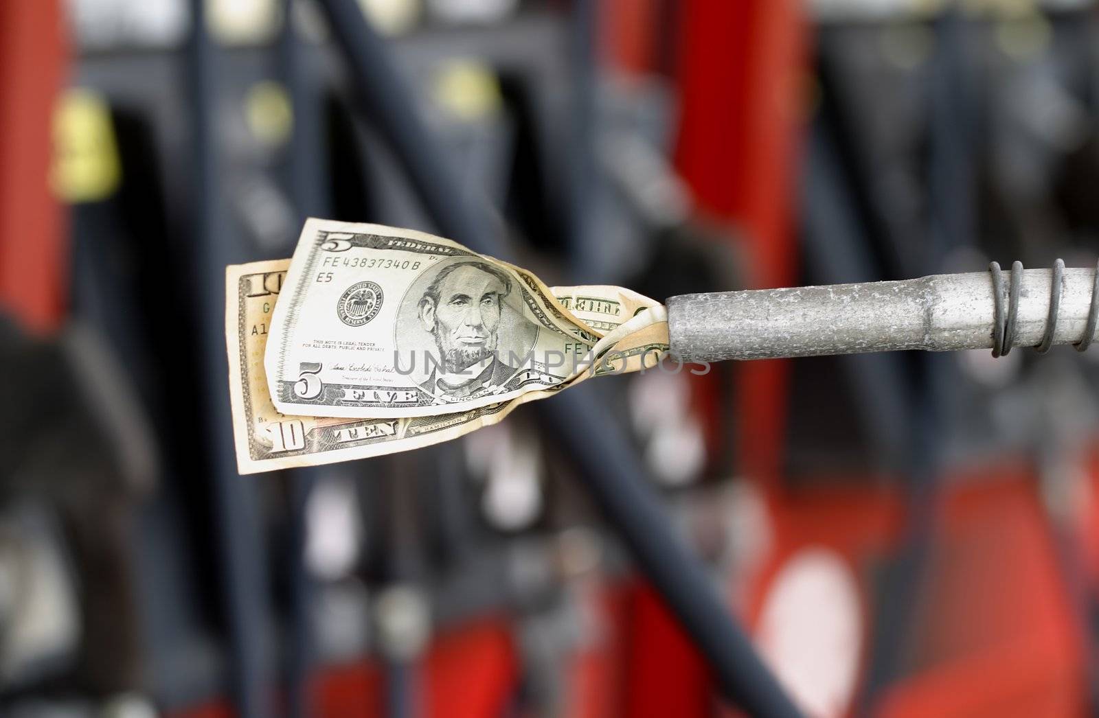 Dollars displayed in a gas pump with pumps in background.