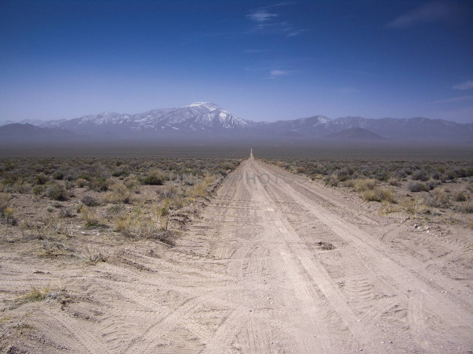 Desert vista of snowy mountains from dirt road Nevad USA