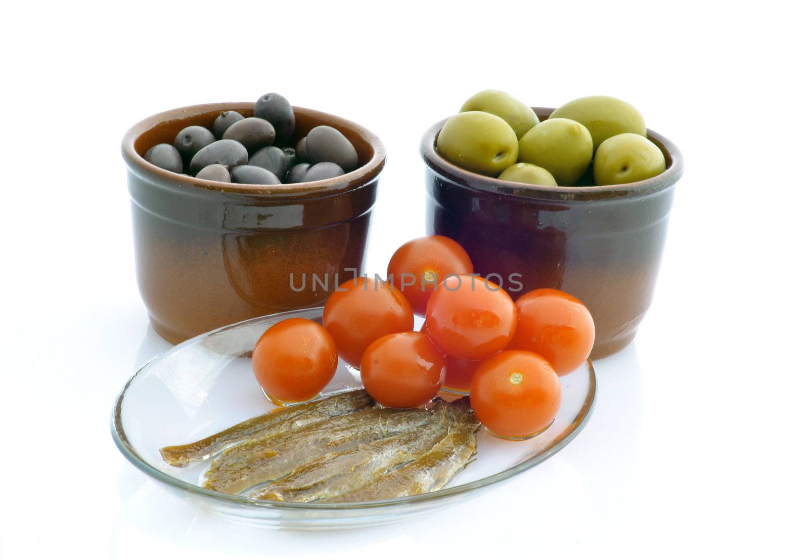 Green and black olives, tomatoes and anchovies on white backgrounds