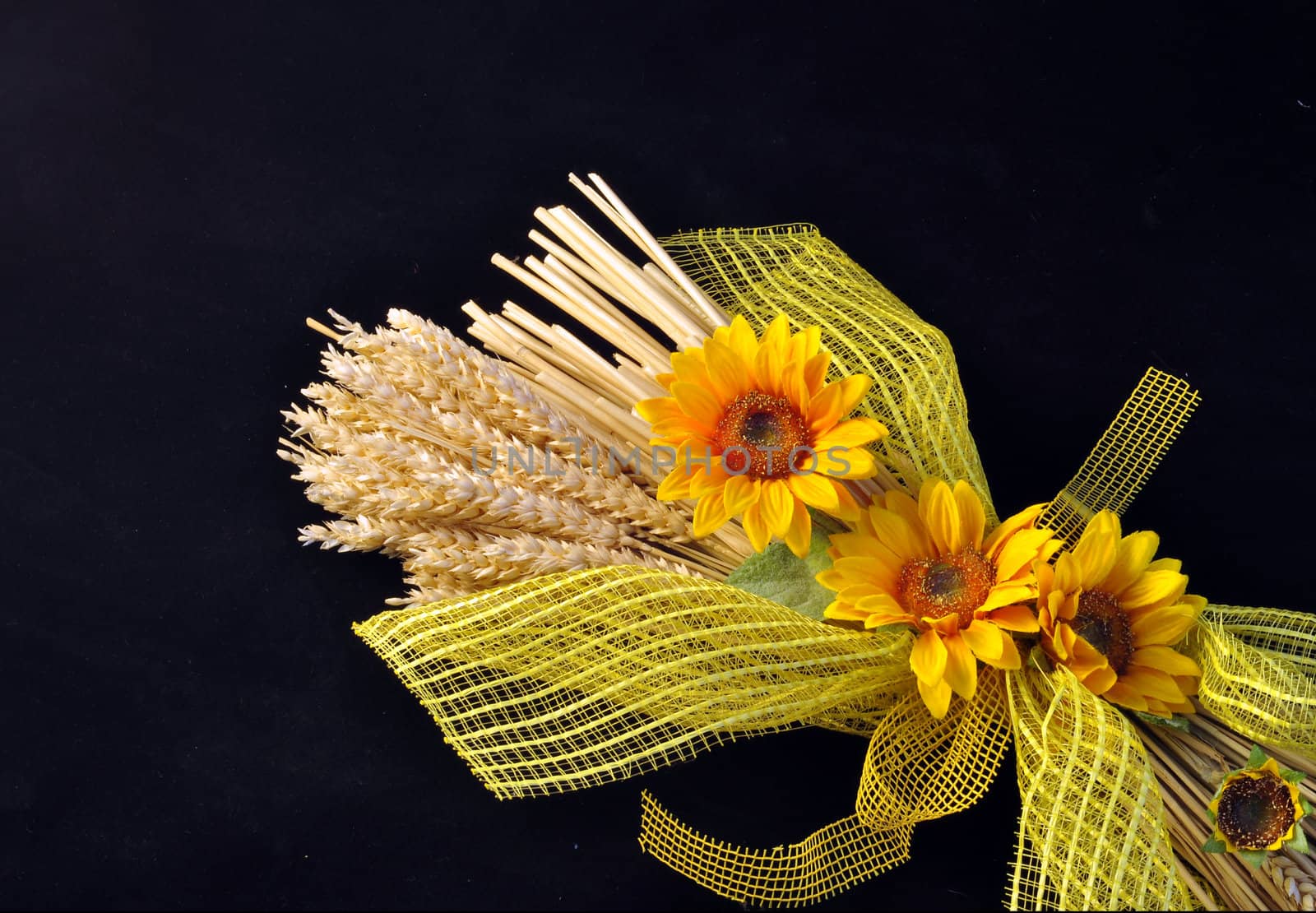 Decoration consists of stalks of wheat and sunflowers on a black background.
