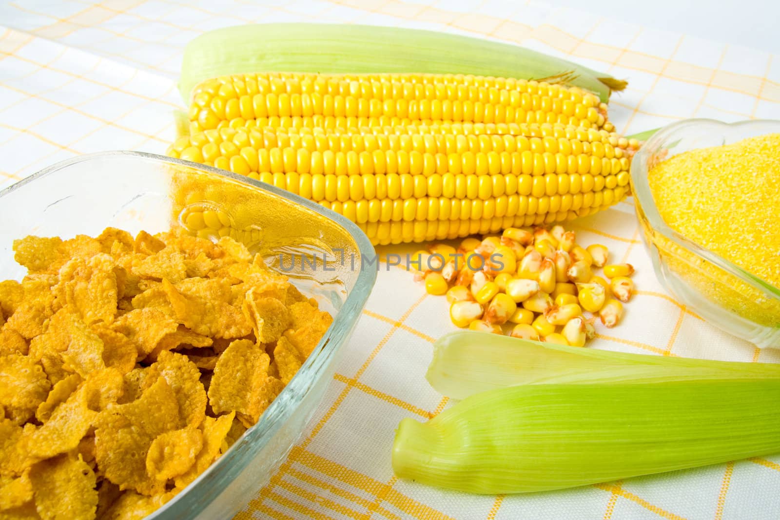Fresh maize corn with leaves and cornflakes in bowl.