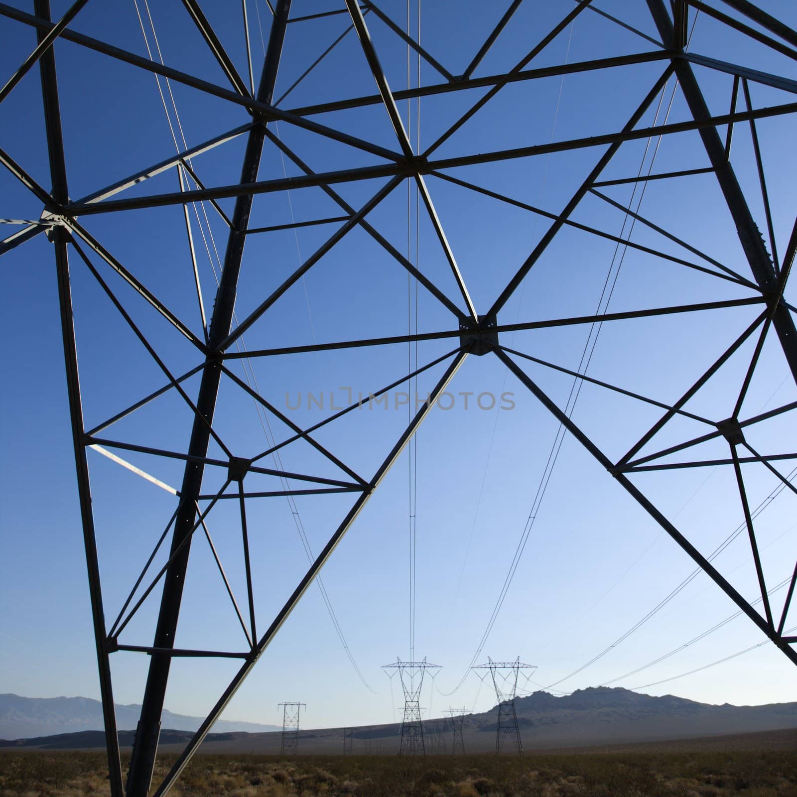 Electrical power lines in barren desert landscape.