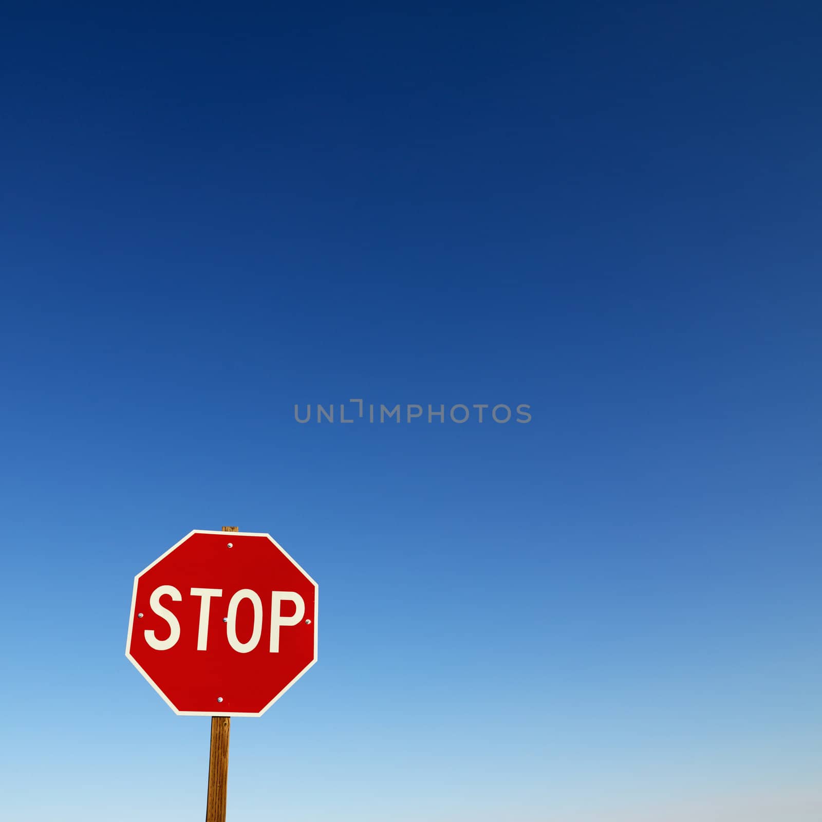 Stop sign in lower left corner with blue sky all around.