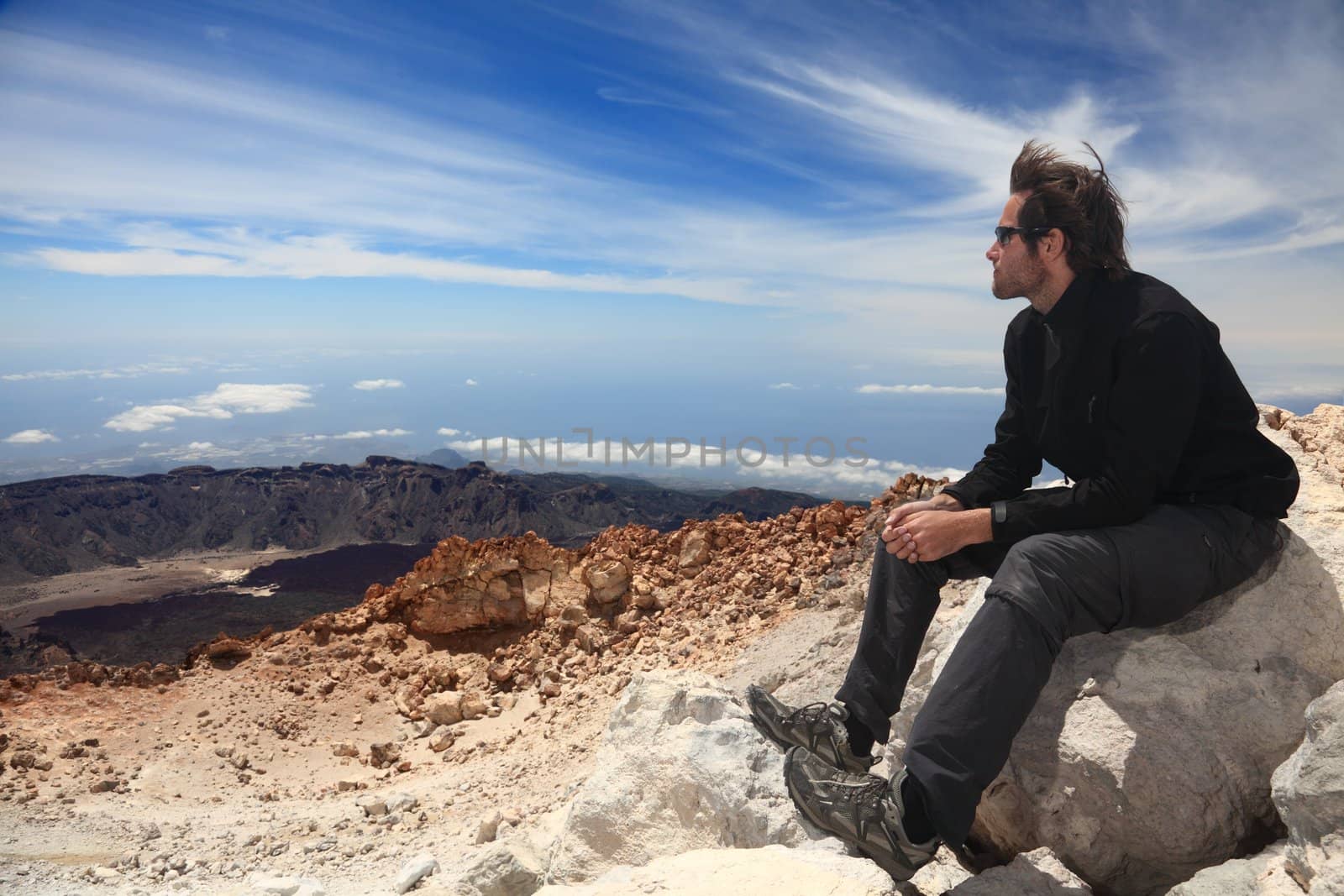 Hiking - Hiker enjoying view. Male hiker sitting and relaxing at the summit of the volcano 
Teide on Tenerife.