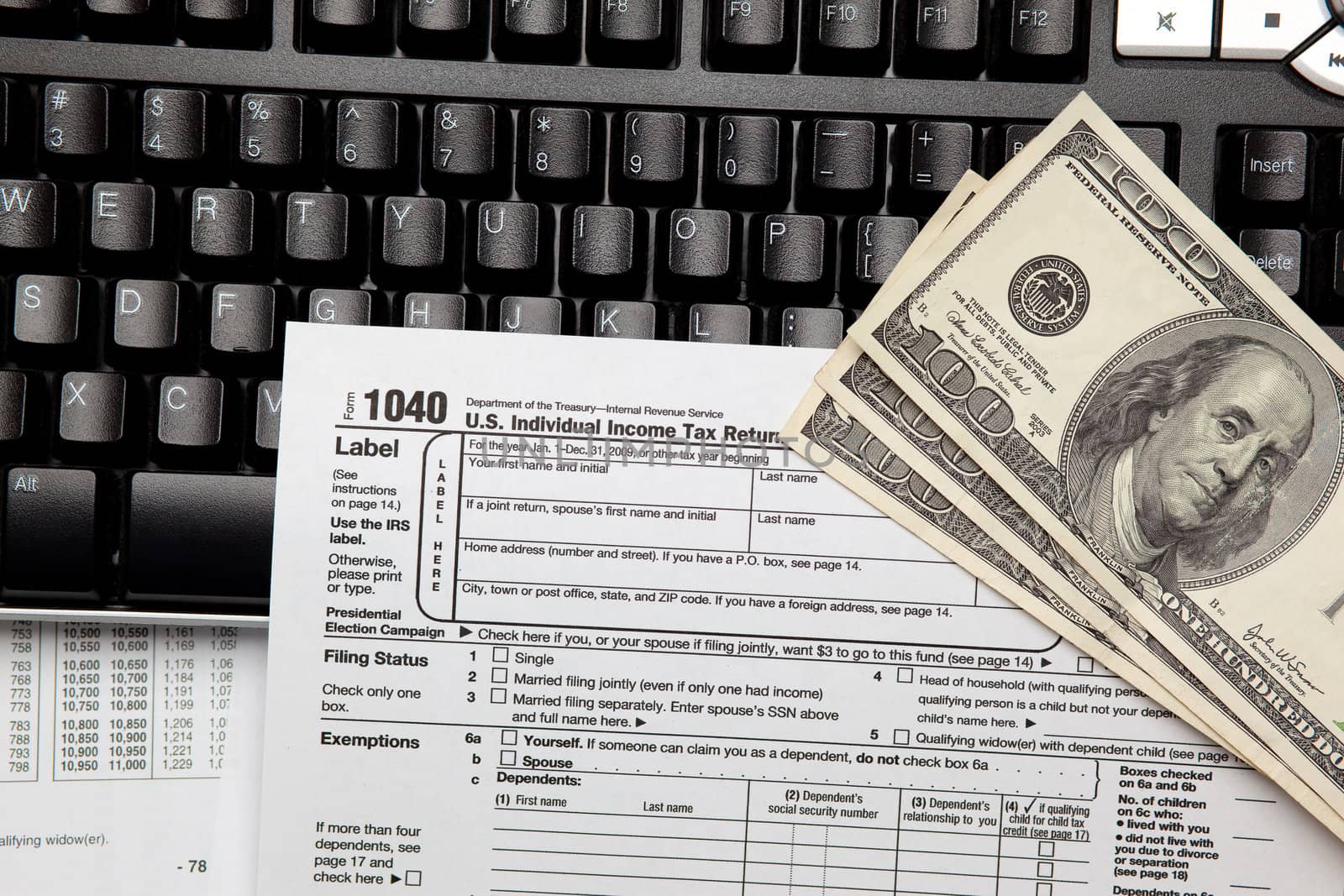 Tax time - Closeup of U.S. 1040 tax return with $100 bills and computer keyboard