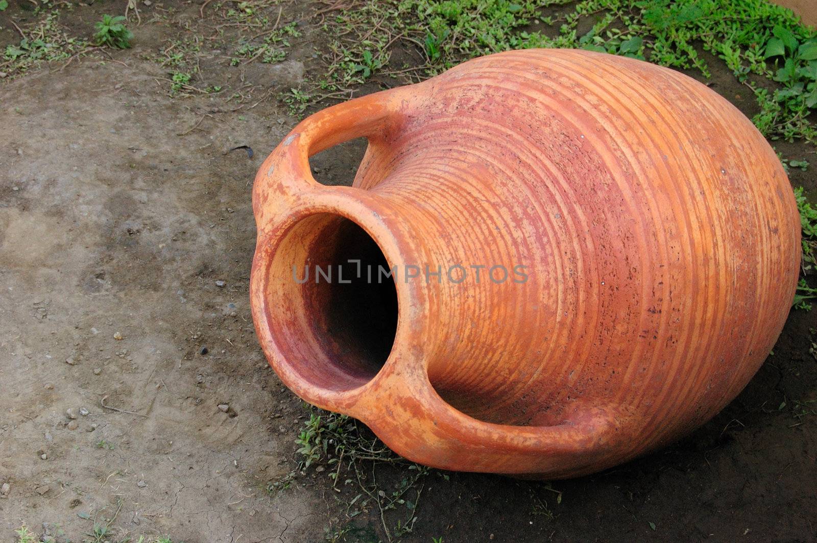 old-style greek amphora laying on earth