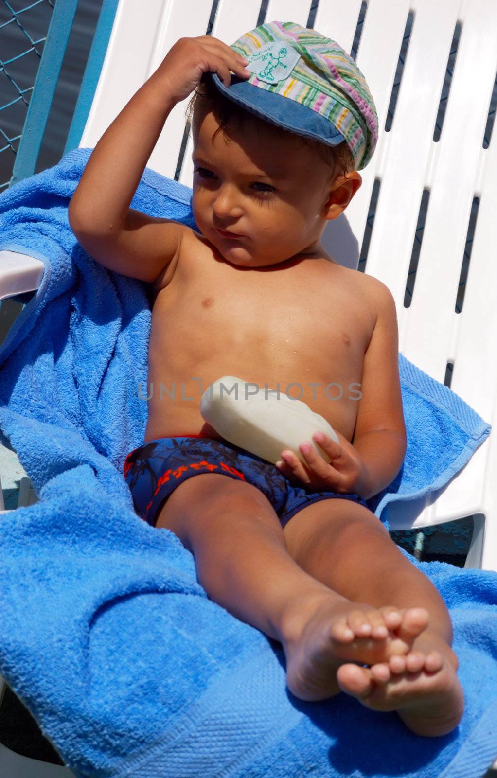 little boy sitting in the beach chair with blue towel