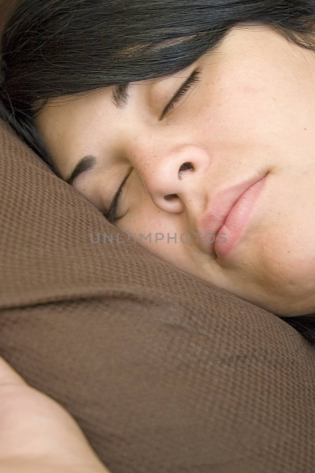 A young brunette woman is fast asleep in her bed.