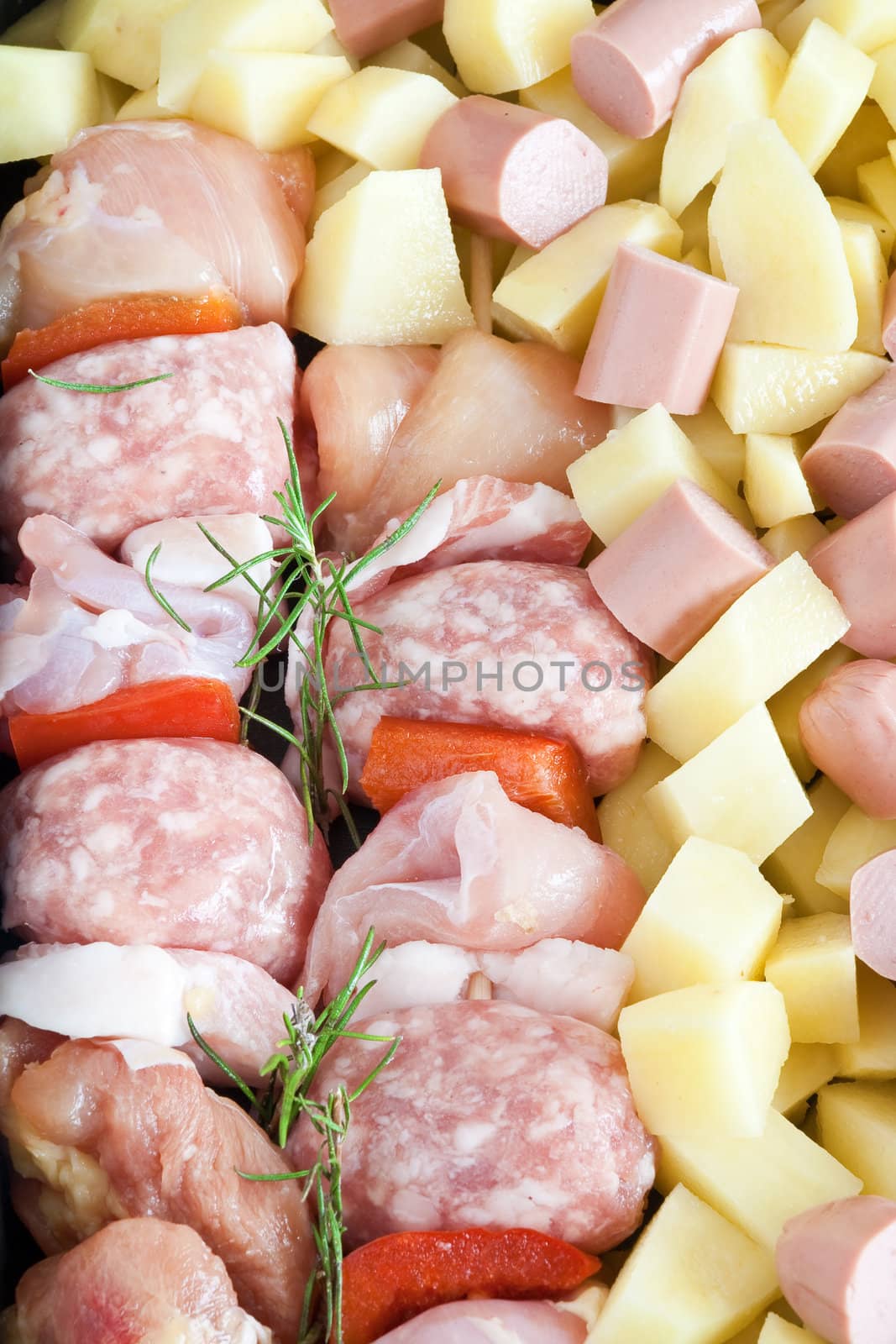 detail of raw pork kebab with sliced potatoes, wurstel and rosemary