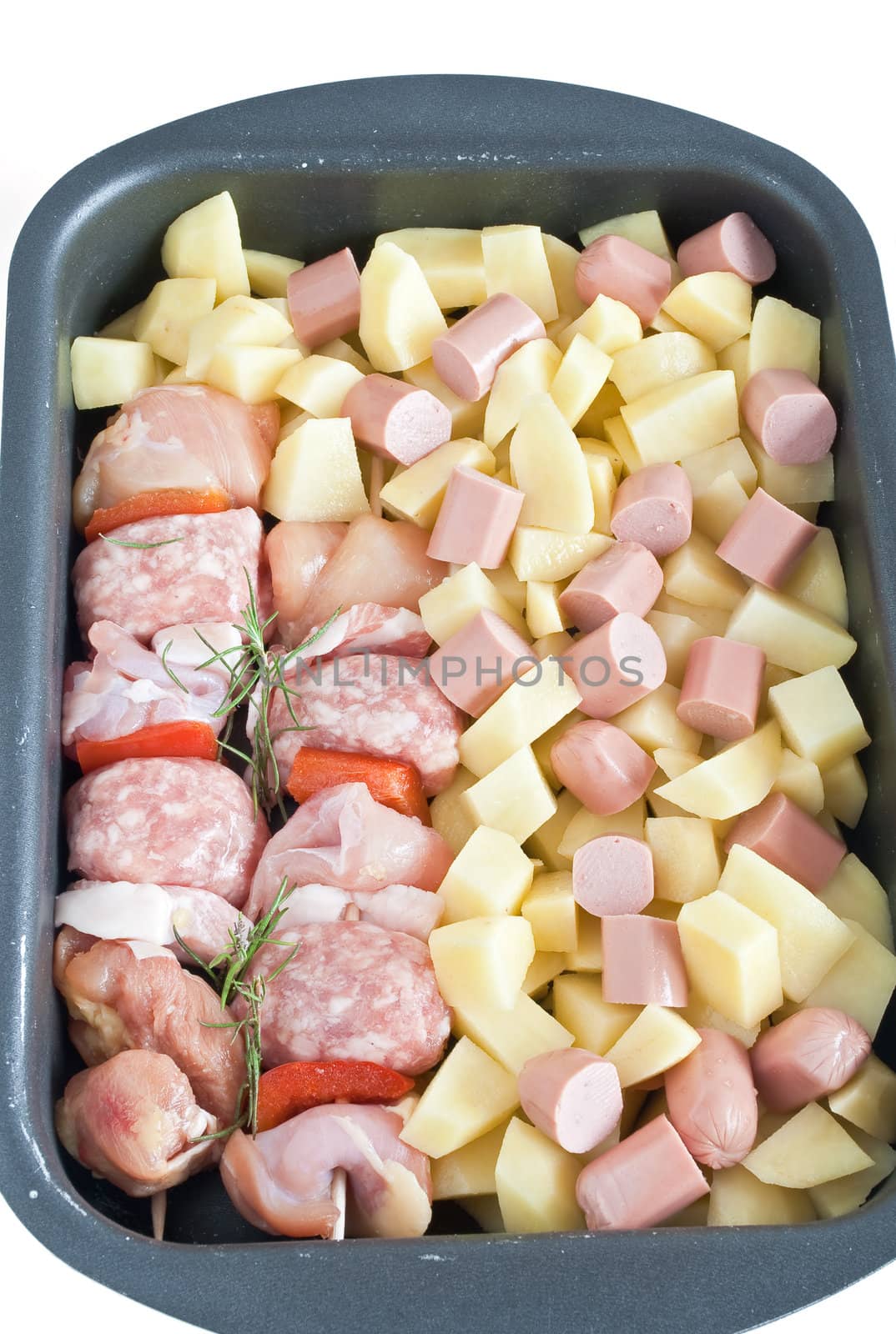 detail of raw pork kebab with sliced potatoes, wurstel and rosemary