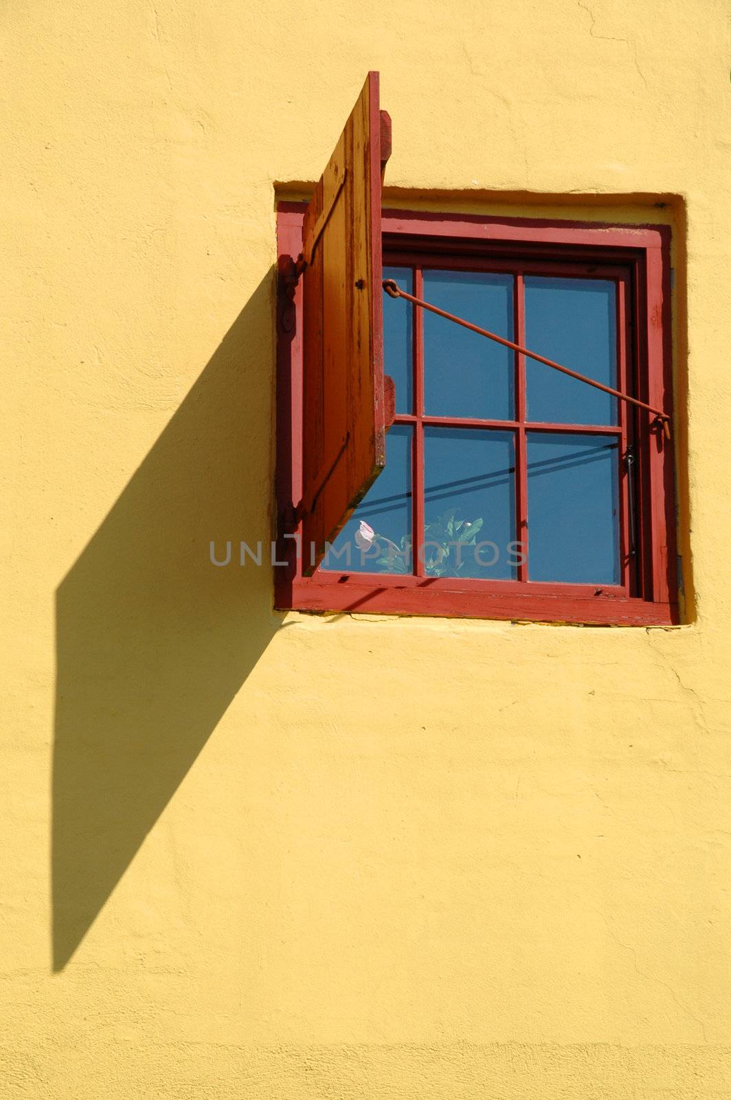 Window and shadow. The window is red and the wall is yellow.