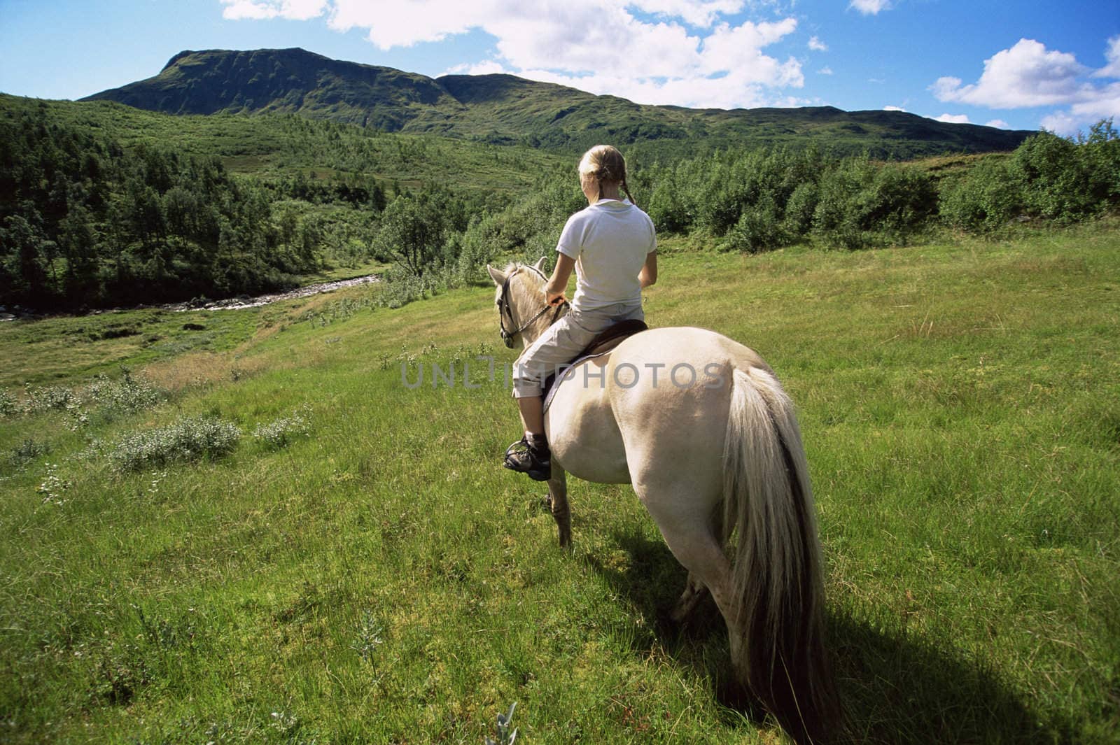 Woman outdoors riding horse in scenic location  by MonkeyBusiness