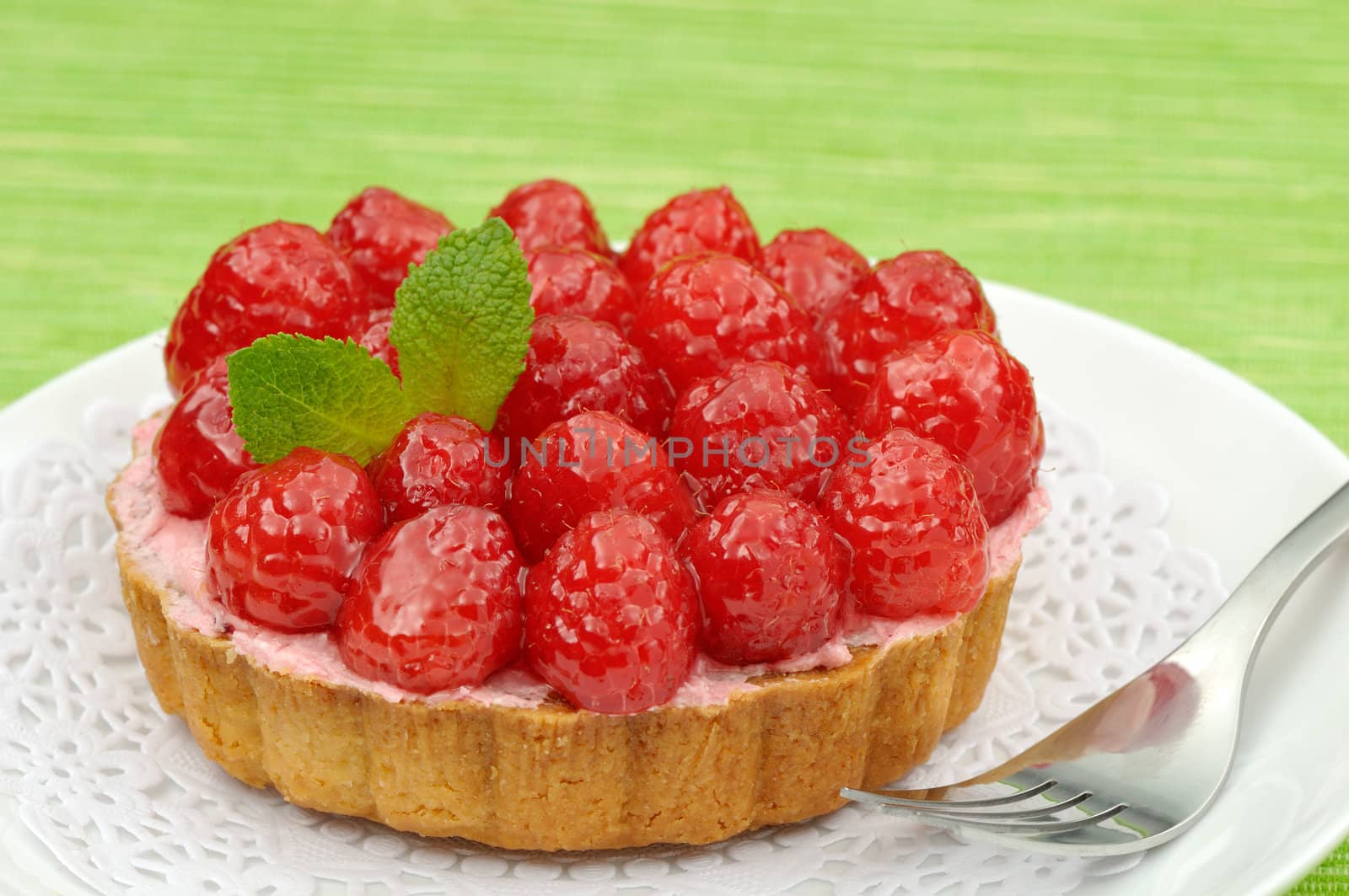 Fruit tartlet on a plate and green background