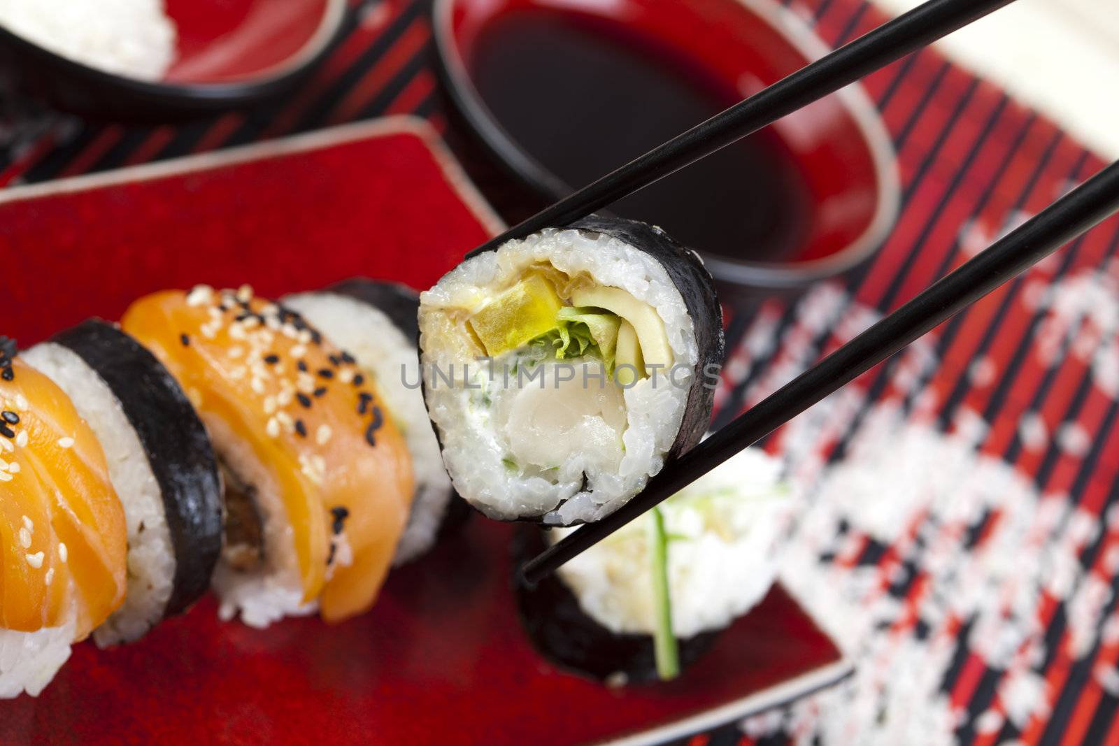 Tuna roll on square green plate with wasabi and ginger. Soy dipping bowl in background. Shot with very shallow depth of field