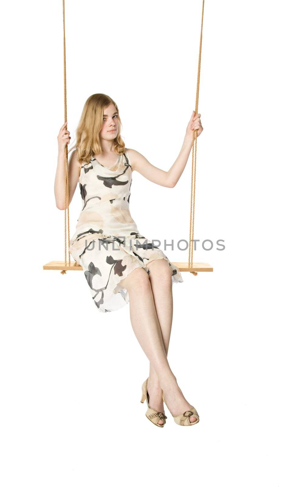 Young blonde sitting on a swing, white background