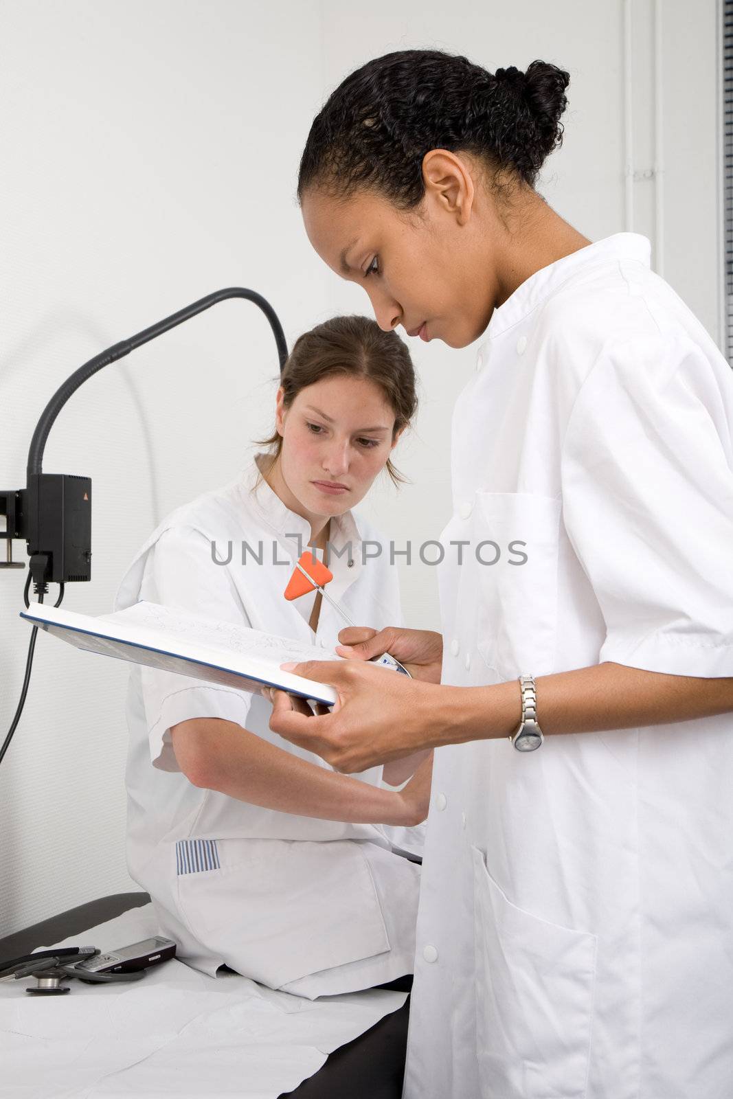 Two doctors looking through the book to find something