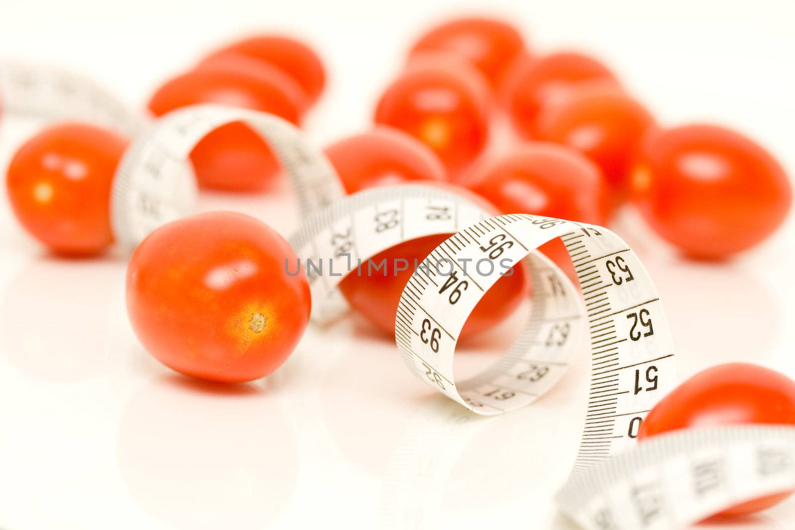 Small tomatoes on white with tape measure