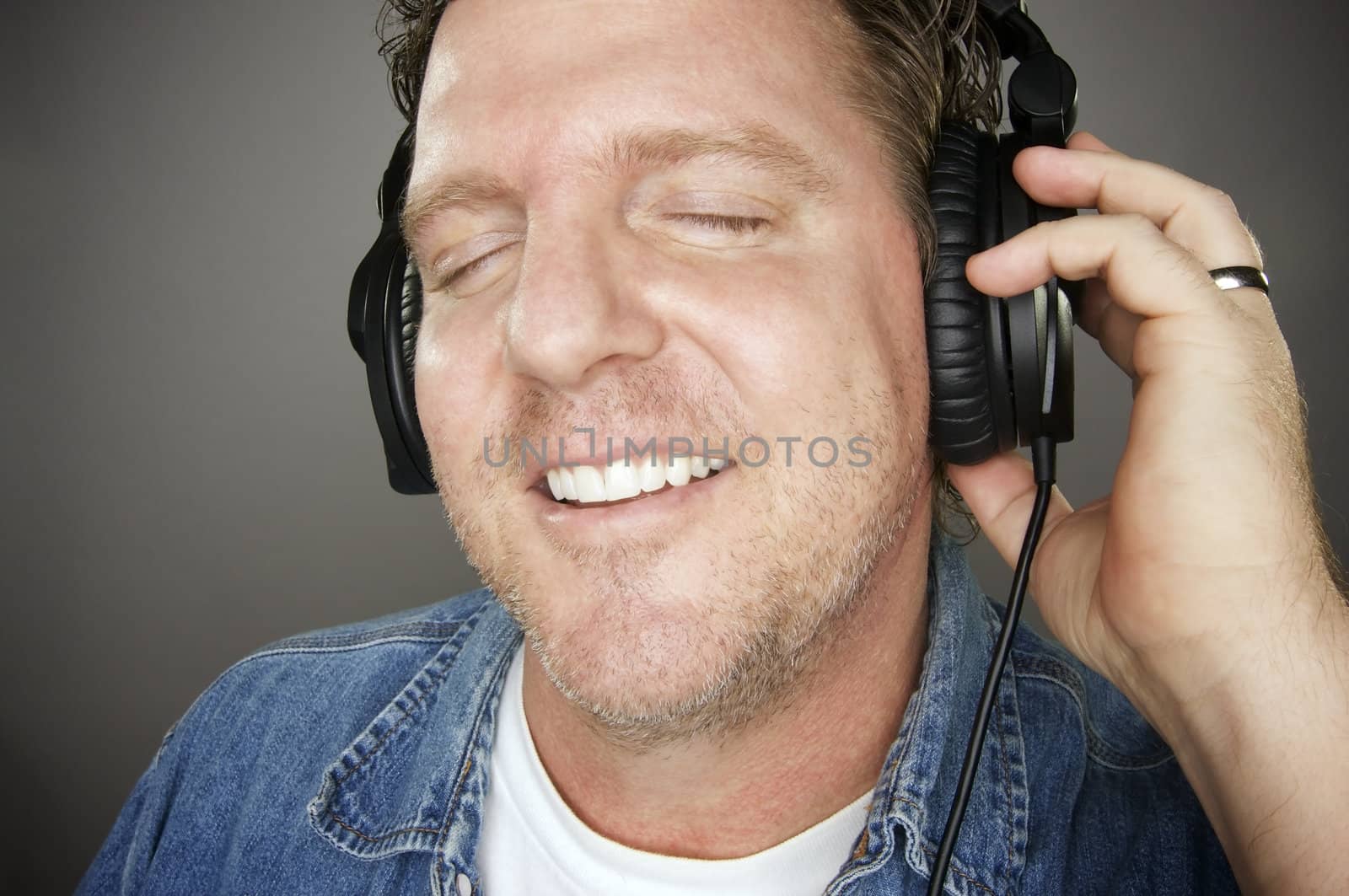 Man Wearing Headphones Enjoying His Music on a Grey Background.