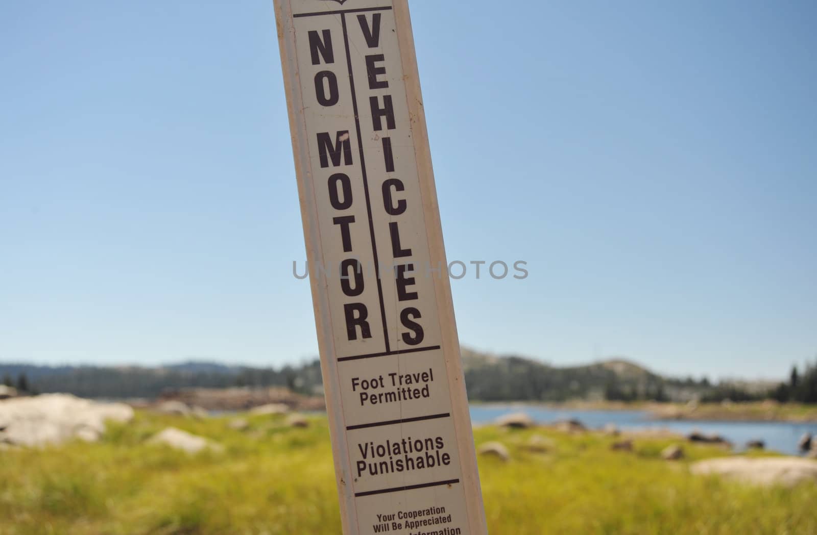 A No Motor Vehicles sign stand at the shoreline of a Sierra lake