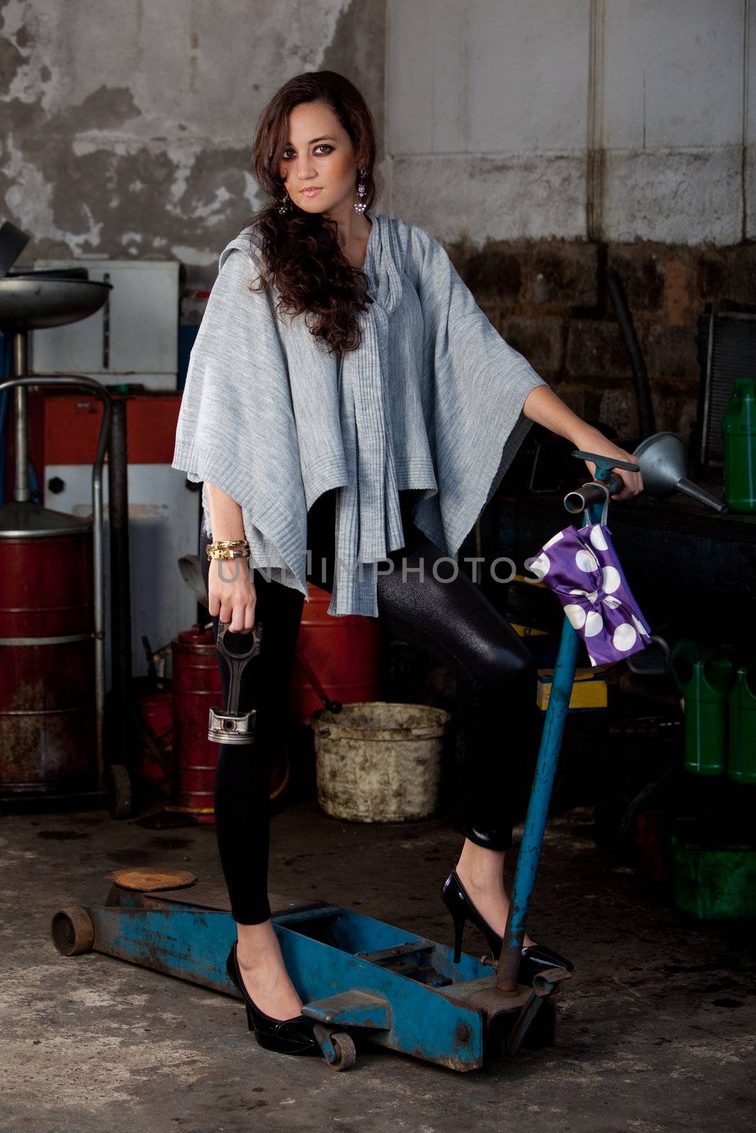 A young brazilian female model shot in a dirty auto repair shop.