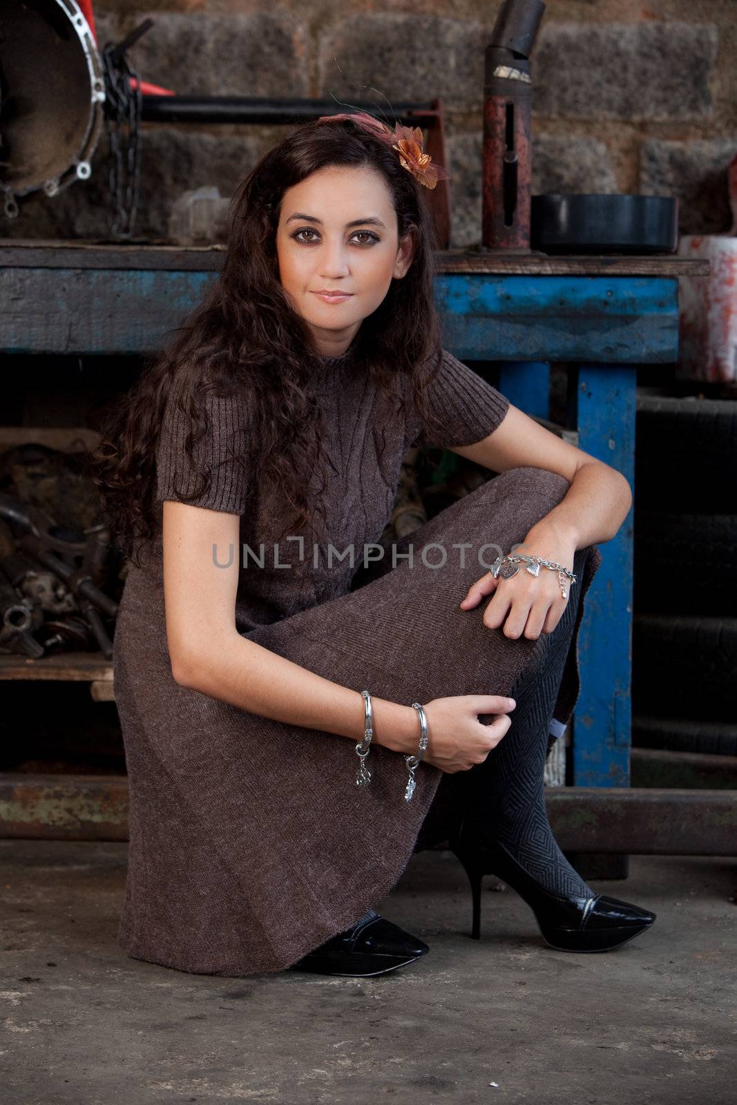 A young brazilian female model shot in a dirty auto repair shop.