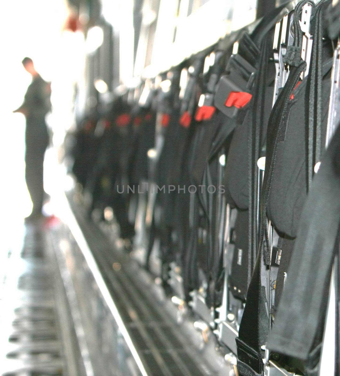 A row of jump seats folded up on C-5 airforce cargo plane. A soldier stands in the background out of focus.