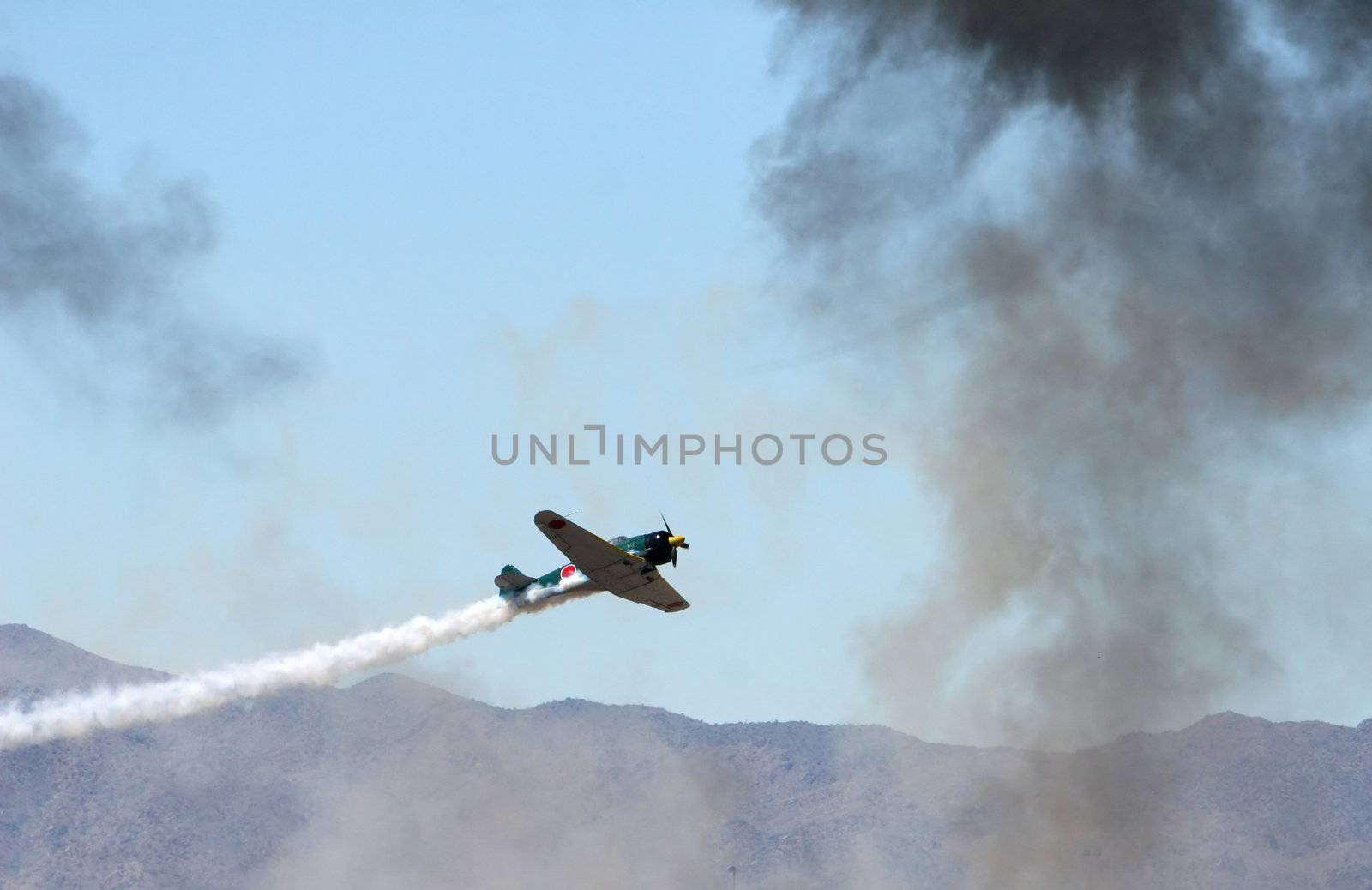 An old japanese warplane flys through heavy smoke during a simulated attack