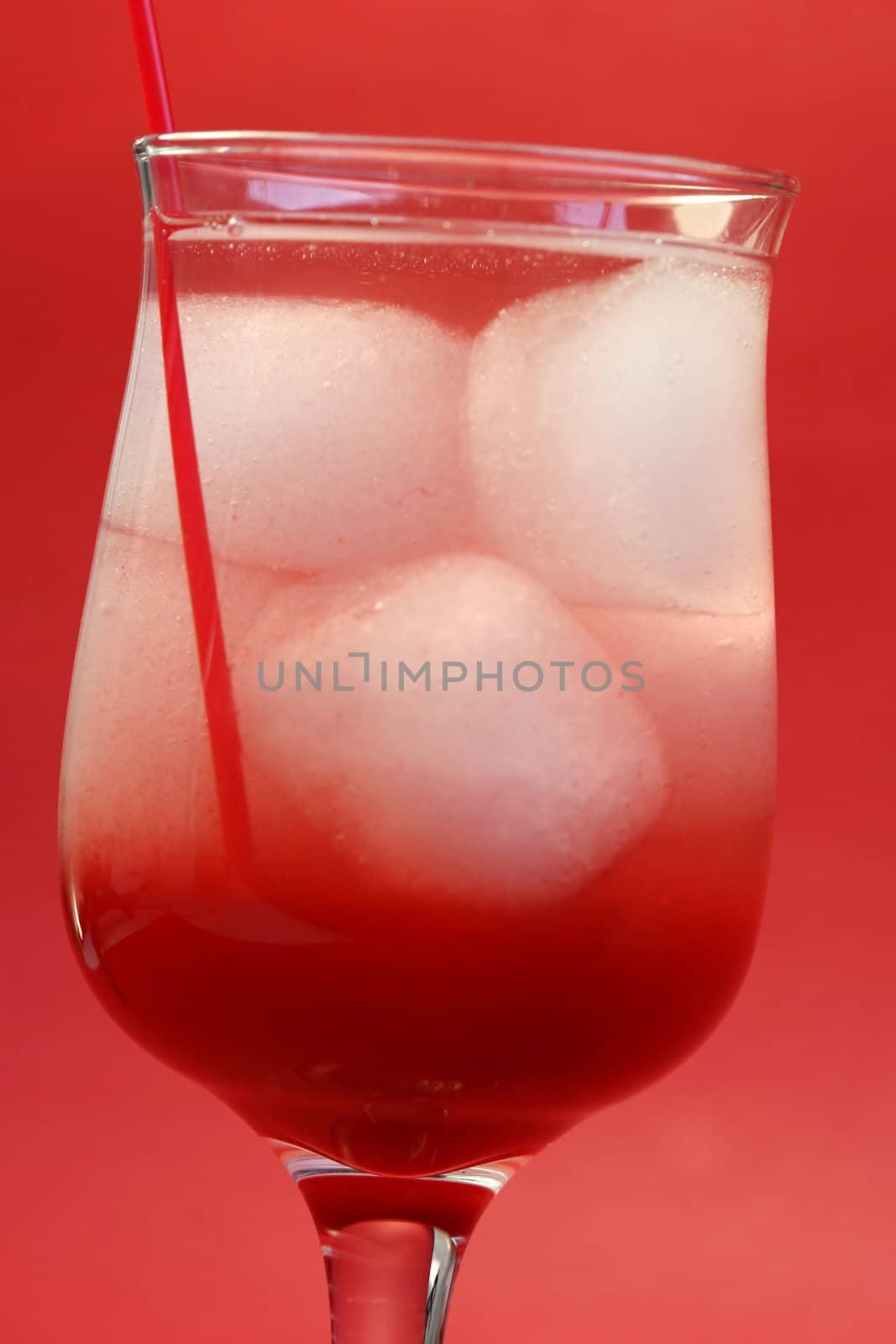 A delicious red cocktail drink on ice. Served in a tall stem daiquiri glass