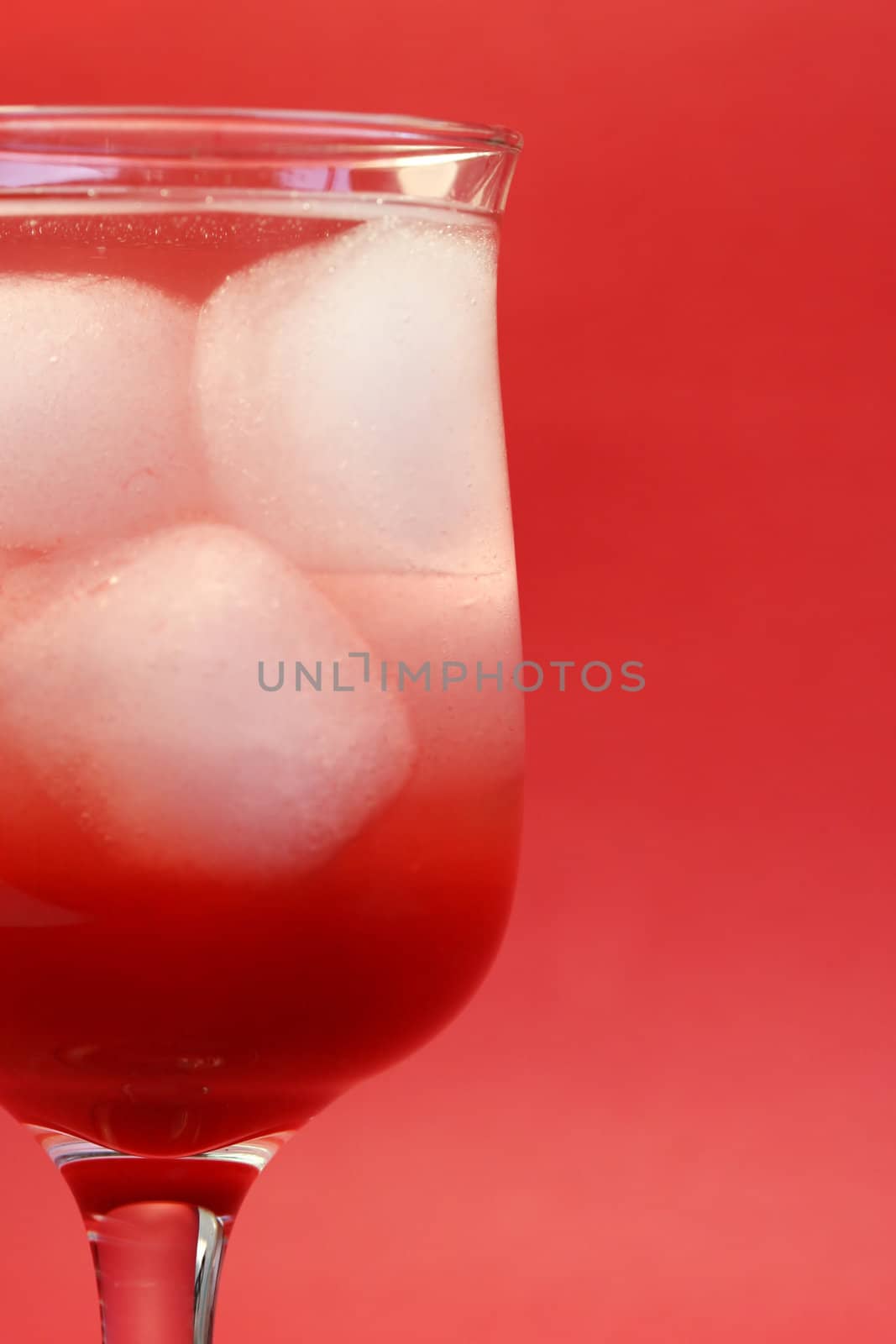 A delicious red cocktail drink on ice. Served in a tall stem daiquiri glass