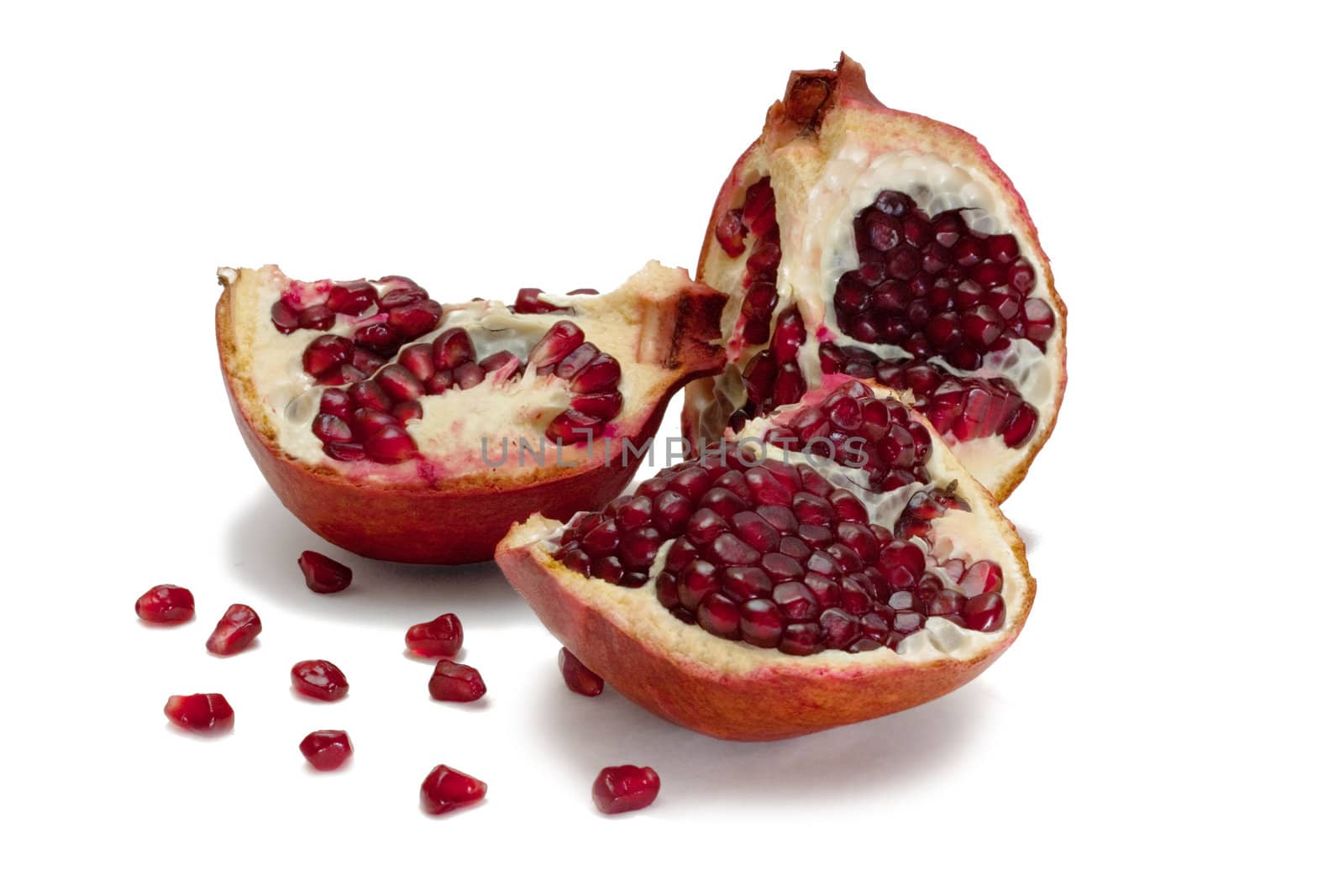 Parts of pomegranate and seeds around isolated on white