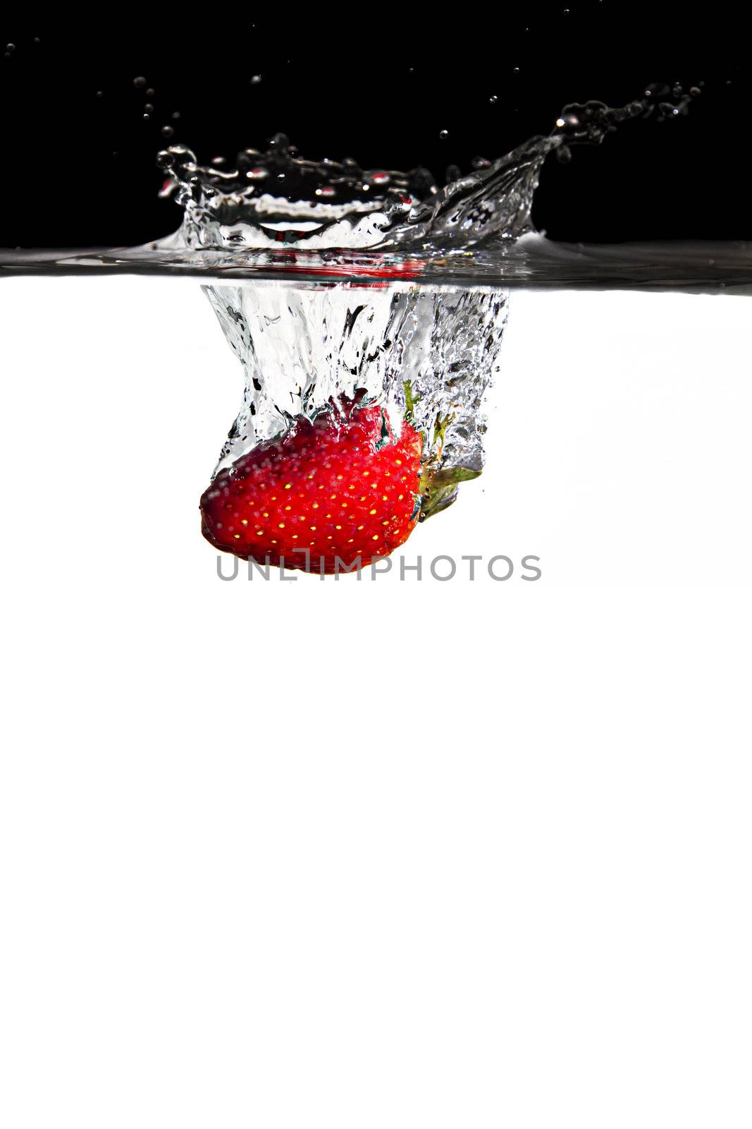 one red strawberry thrown in water with black and white background
