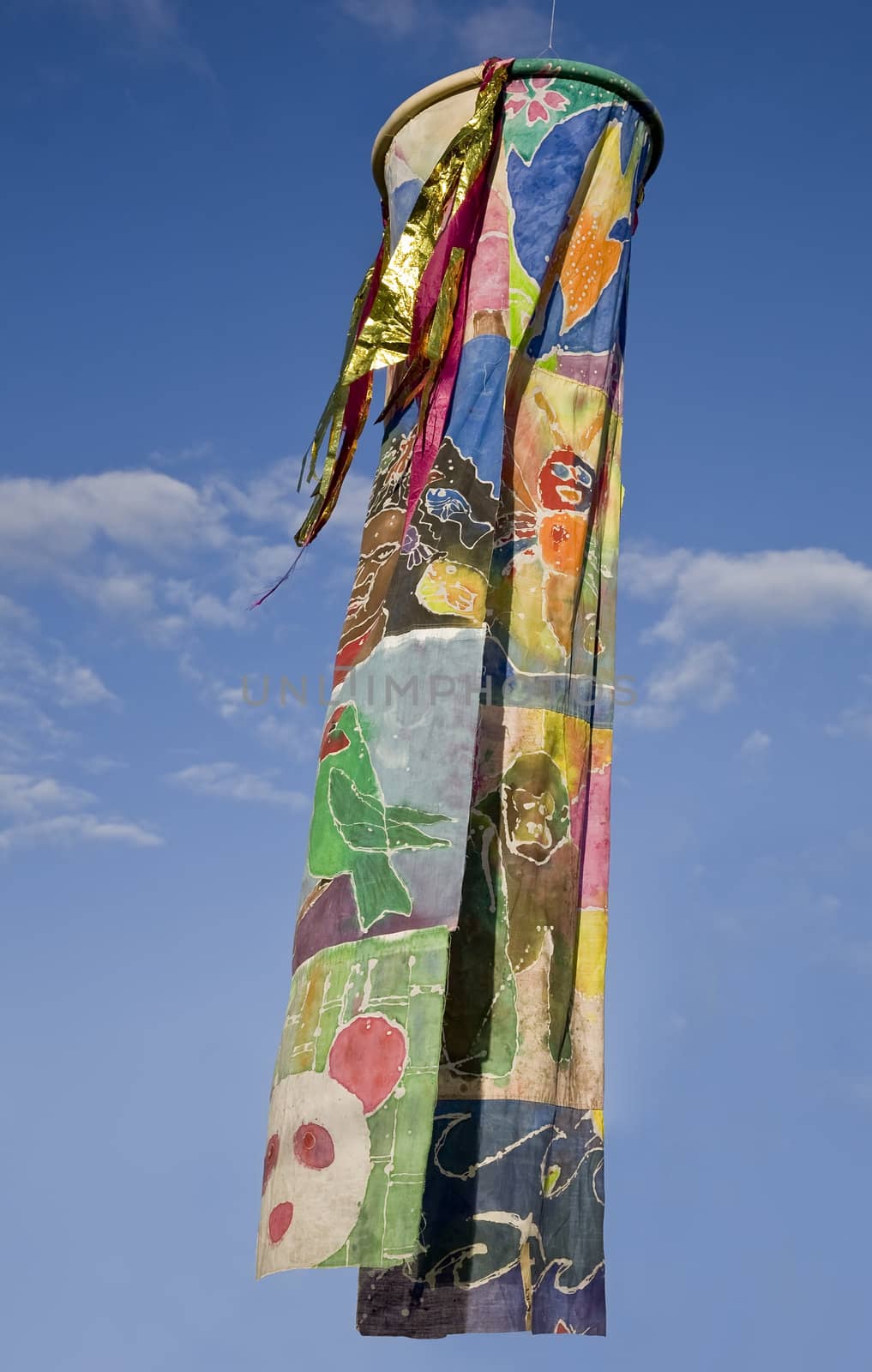 A beautifully colorful windsock hangs against a blue sky
