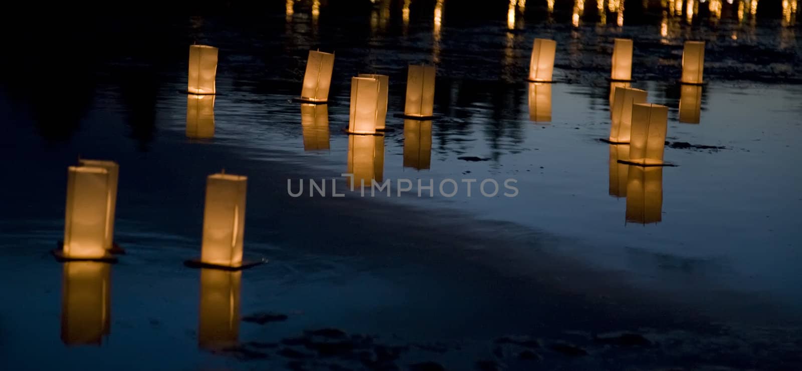 Candlelit floating Japanese lanterns float on a lake
