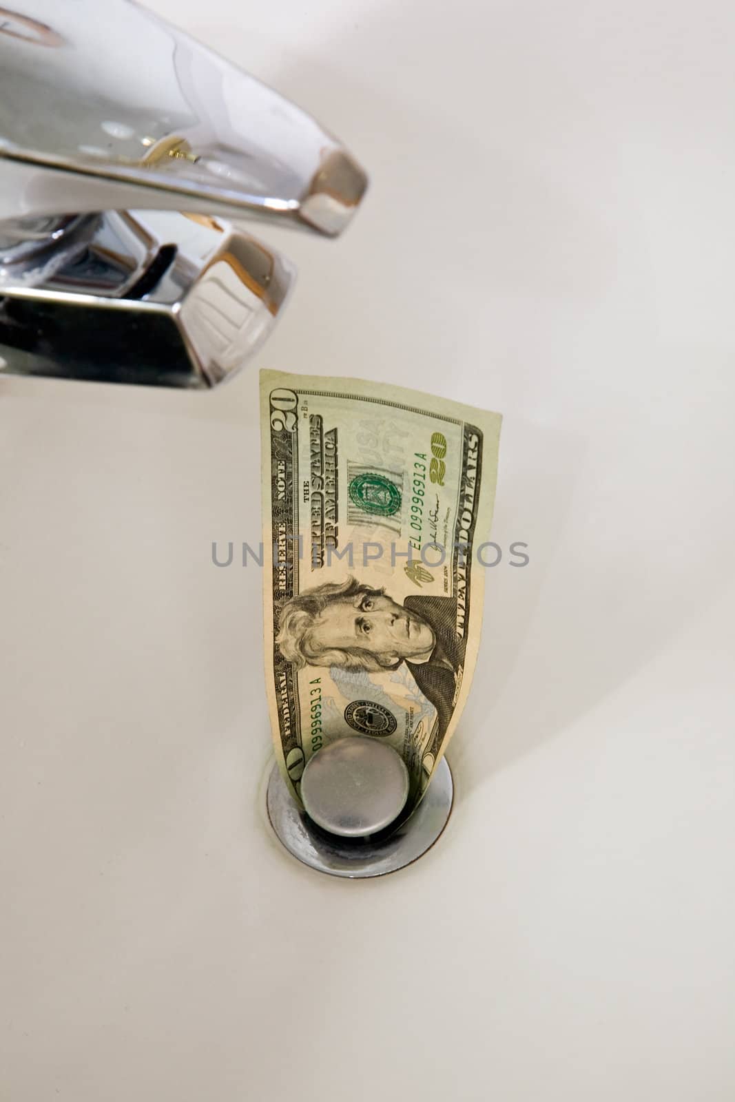 A U.S. twenty dollar bill going down the drain
