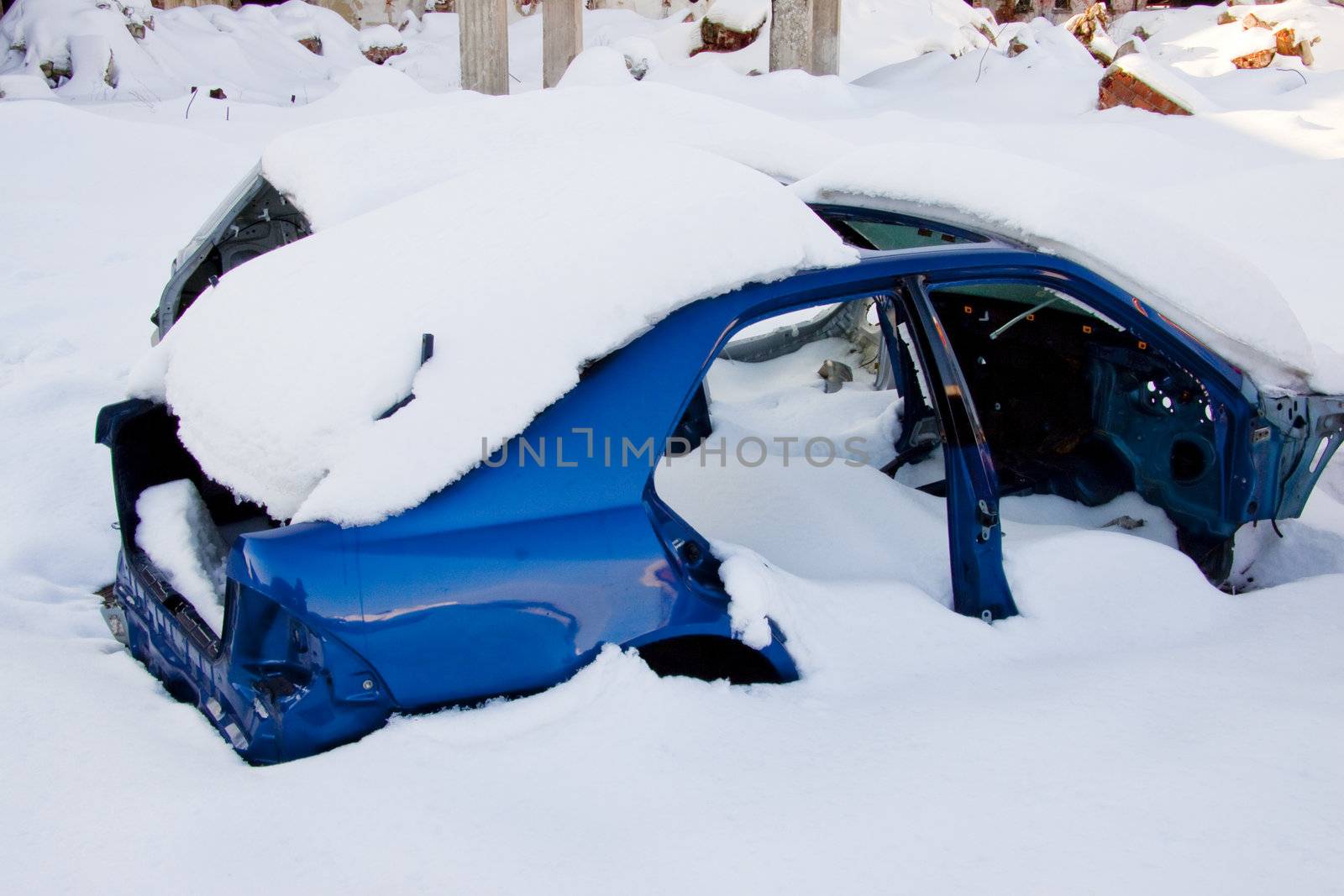 Wasted blue car under white snow in Winter.
