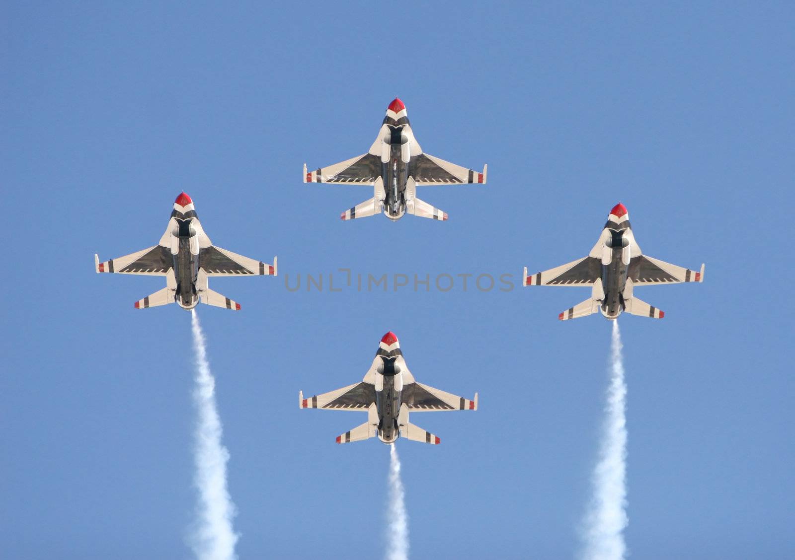 Four fighter jets flying in formation against a clear blue sky