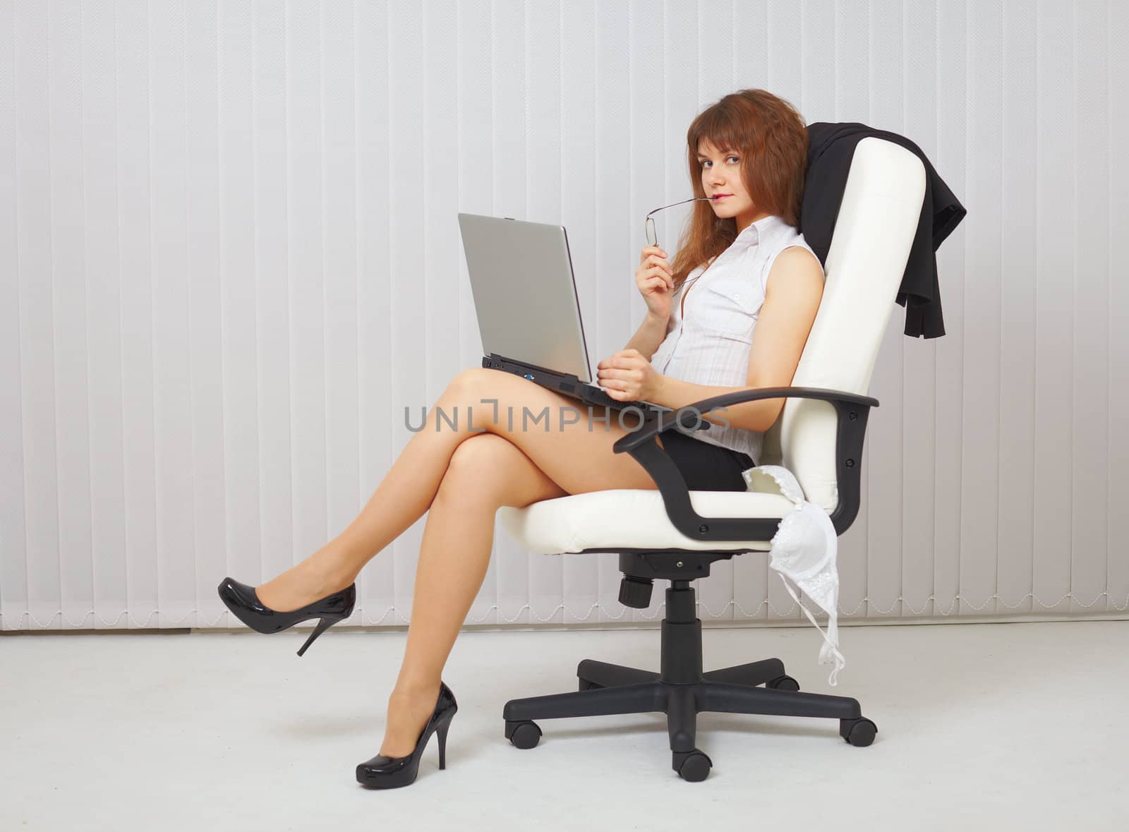 Sexy young woman with a computer in an office chair