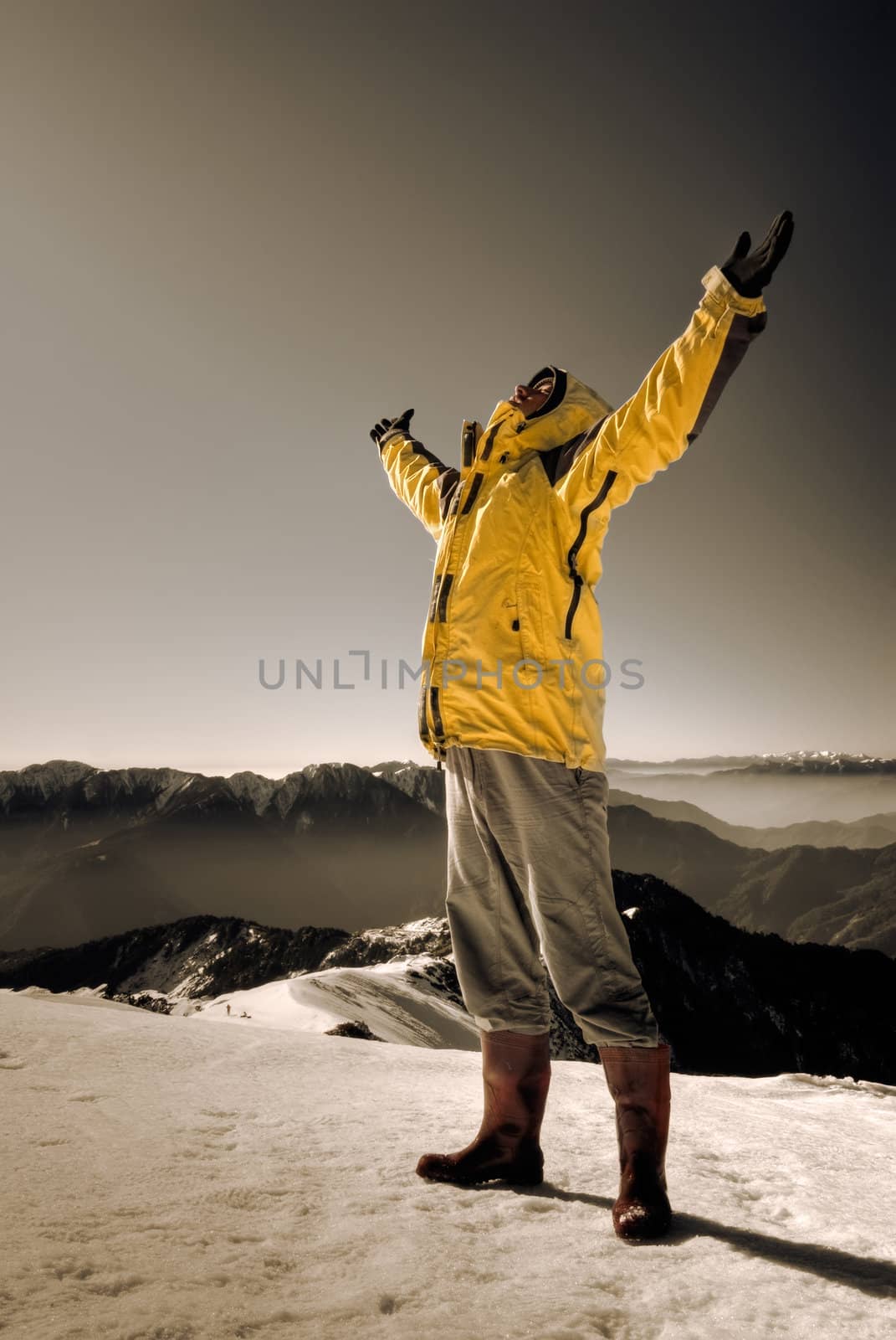 Dramatic scenic with man open arms on snow mountain peak.