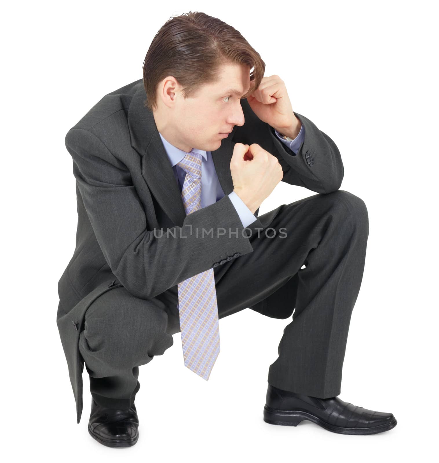 Fighting a businessman sitting in a defensive pose, isolated on a white background
