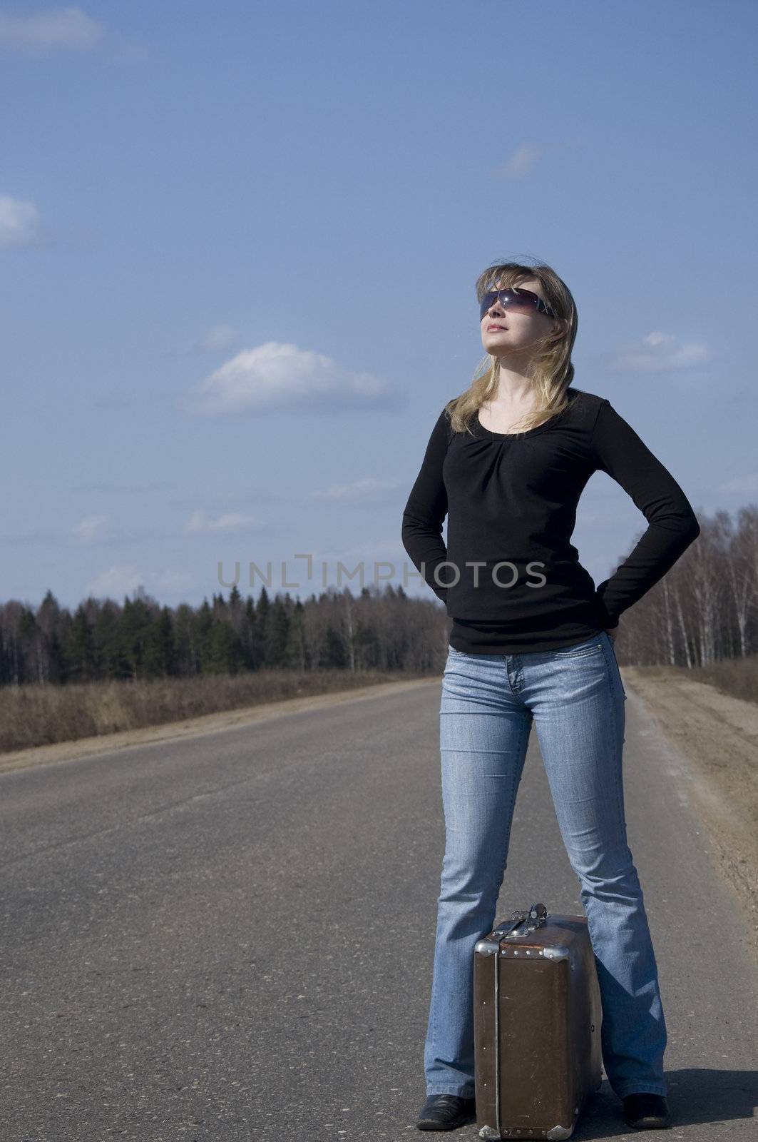 Beautiful country girl waiting on the road with her baggage
