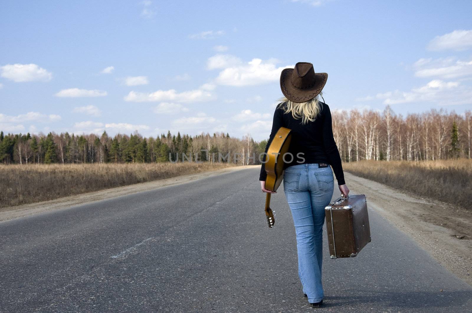 country girl with guitar goes on road solitary under sky